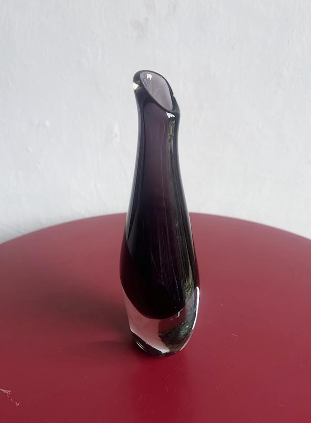 The piece features a deep purple or amethyst color submerged within clear glass, creating a striking visual effect through layering different colored glass. Such decorative art glass pieces became highly sought after during the mid-century modern