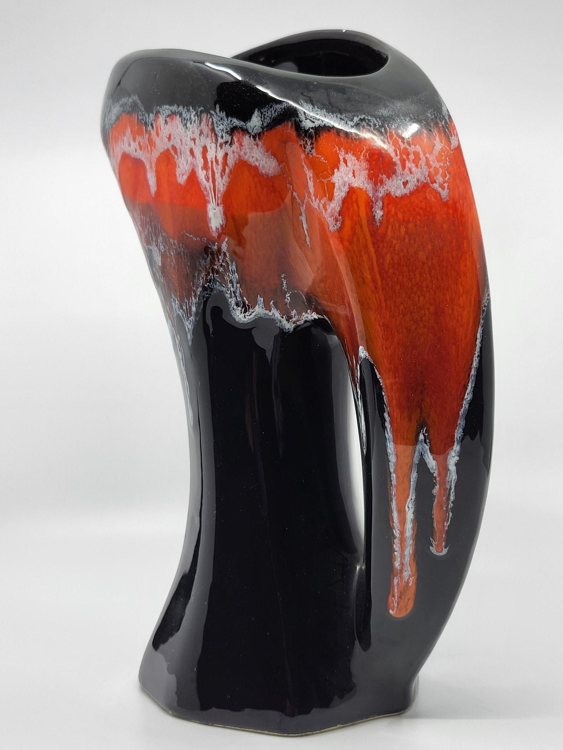Vaso o pichet Vallauris AM, fondo nero con un decoro di foglie arancioni di vulcano. La sua forma è la più atipica.
L'edificio della fabbrica di Vallauris è una bella rappresentazione dell'Età dell'oro.  delle creazioni francesi del 1950 .
È in