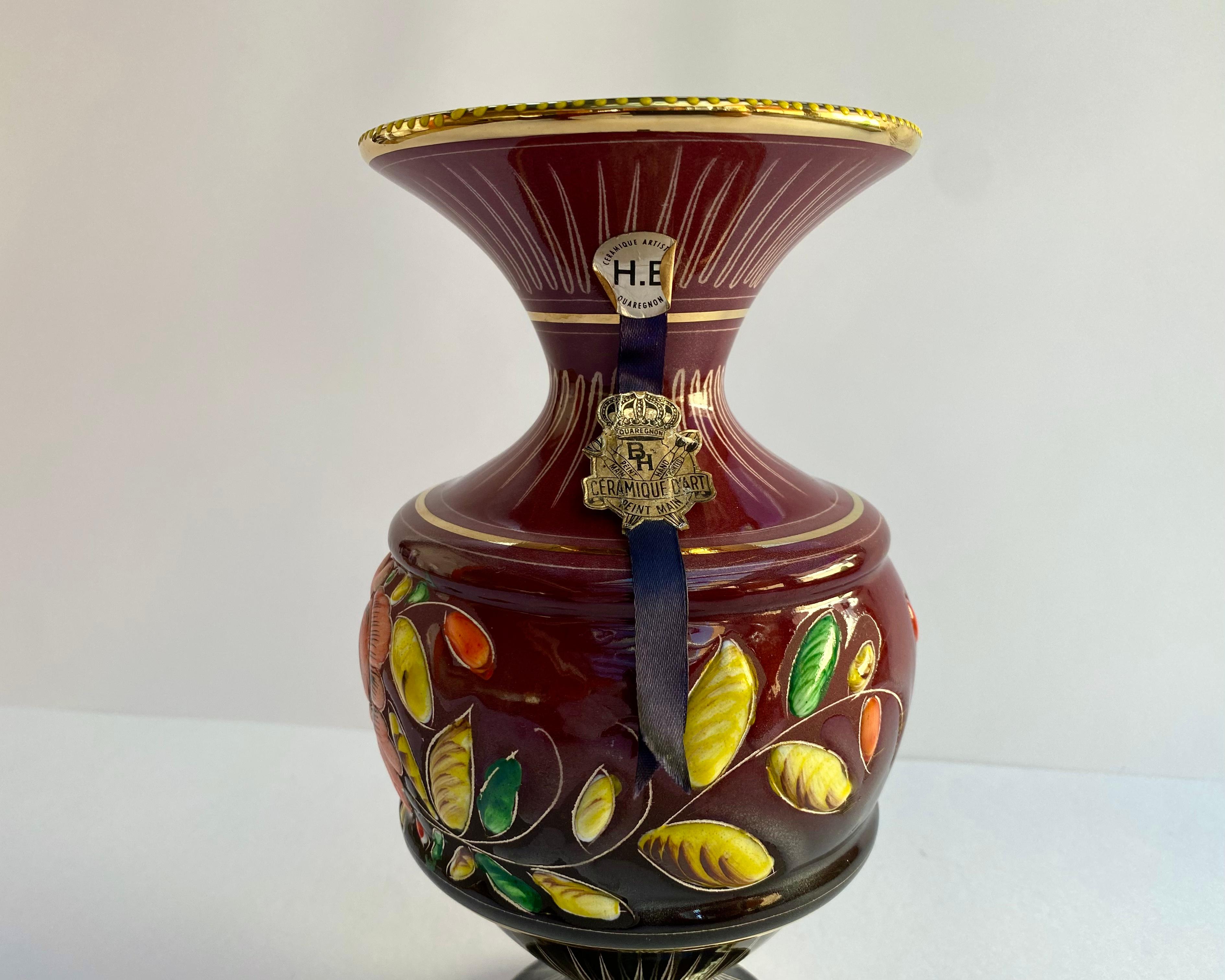 Vase en céramique des années 1950, attribué à Hubert Bequet Quaregnon, avec un beau fond bordeaux décoré d'un motif émaillé en relief de couleurs vives représentant des fleurs colorées.u2028u2028

Tous les objets sont fabriqués et peints à la