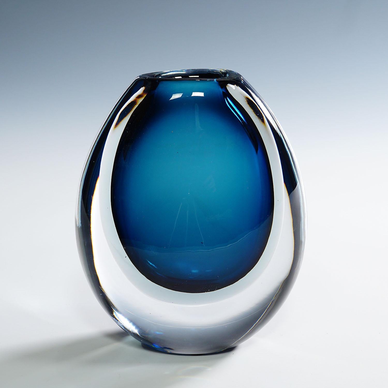 Vase with Blue and Grey Layers, Vicke Lindstrand for Kosta 1950s

A vintage art glass vase designed by Vicke Lindstrand and manufactured by Kosta Glasbruk ca. 1950s. The vase features blue and a grey glass layers with clear glass overlay. The vase