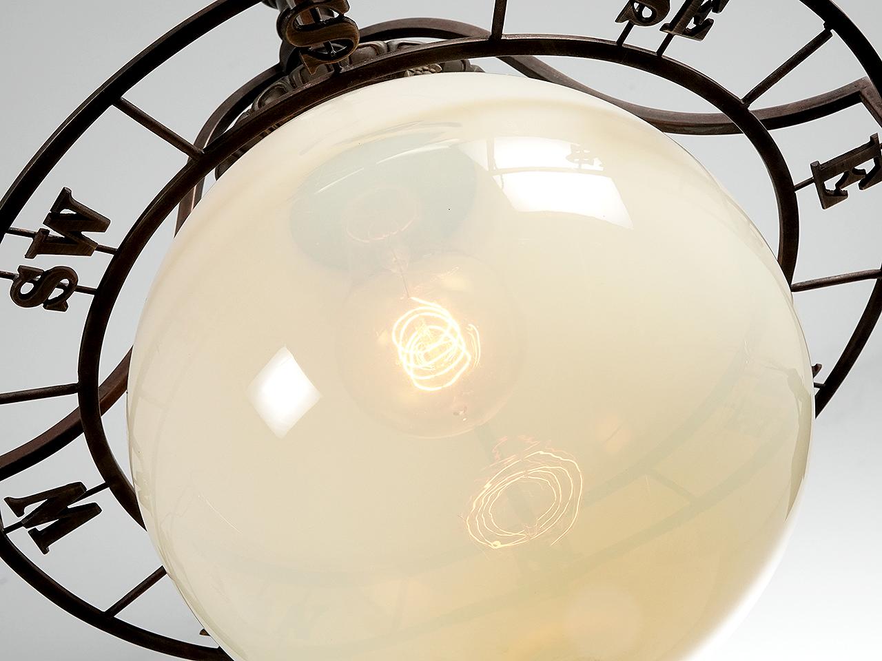 The center shade on this pendent is a translucent Vaseline Glass globe. Tight around the globe is a compass. Most of the other hardware have some nice decorative detail. The lamp looks early and my best guess is 1915 to 1920.
