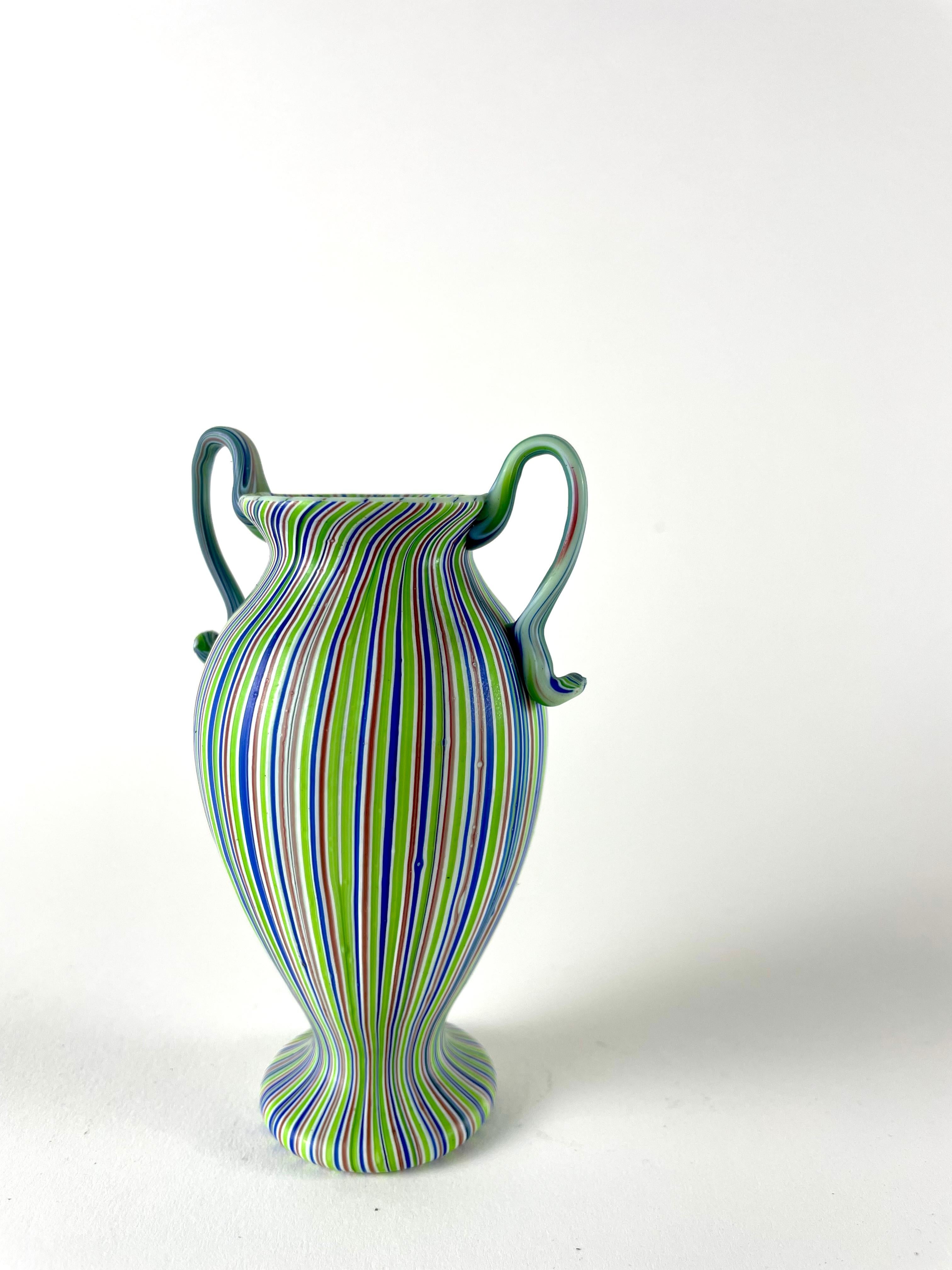 Introducing the Vaso a canne, a small treasure that embodies the incredible craftsmanship of Murano. This exquisite vase is meticulously handcrafted using a unique technique, with small glass canes arranged in a regular and symmetric pattern. The