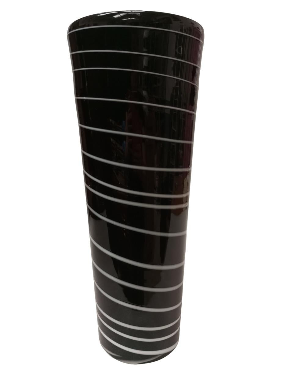 Questo bellissimo vaso alto in vetro di Murano attribuito alla ditta Salviati (Venezia) è un raffinato pezzo vintage in vetro nero, impreziosito da sinuosi vortici bianchi che ne percorrono l'intera superficie. L'oggetto presenta una forma