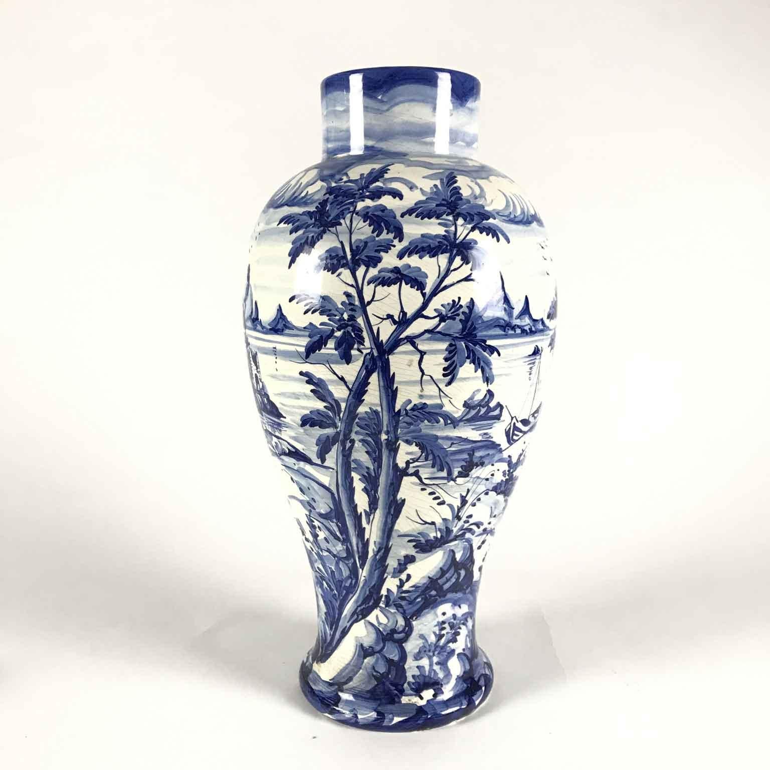 Italian and specifically Florentine vase in White and Blue Ceramic made by the Taccini Family Vinci 1976, as written on the bottom,  decorated in the round with a lake landscape, with trees in the foreground, boats and mountains in the background.