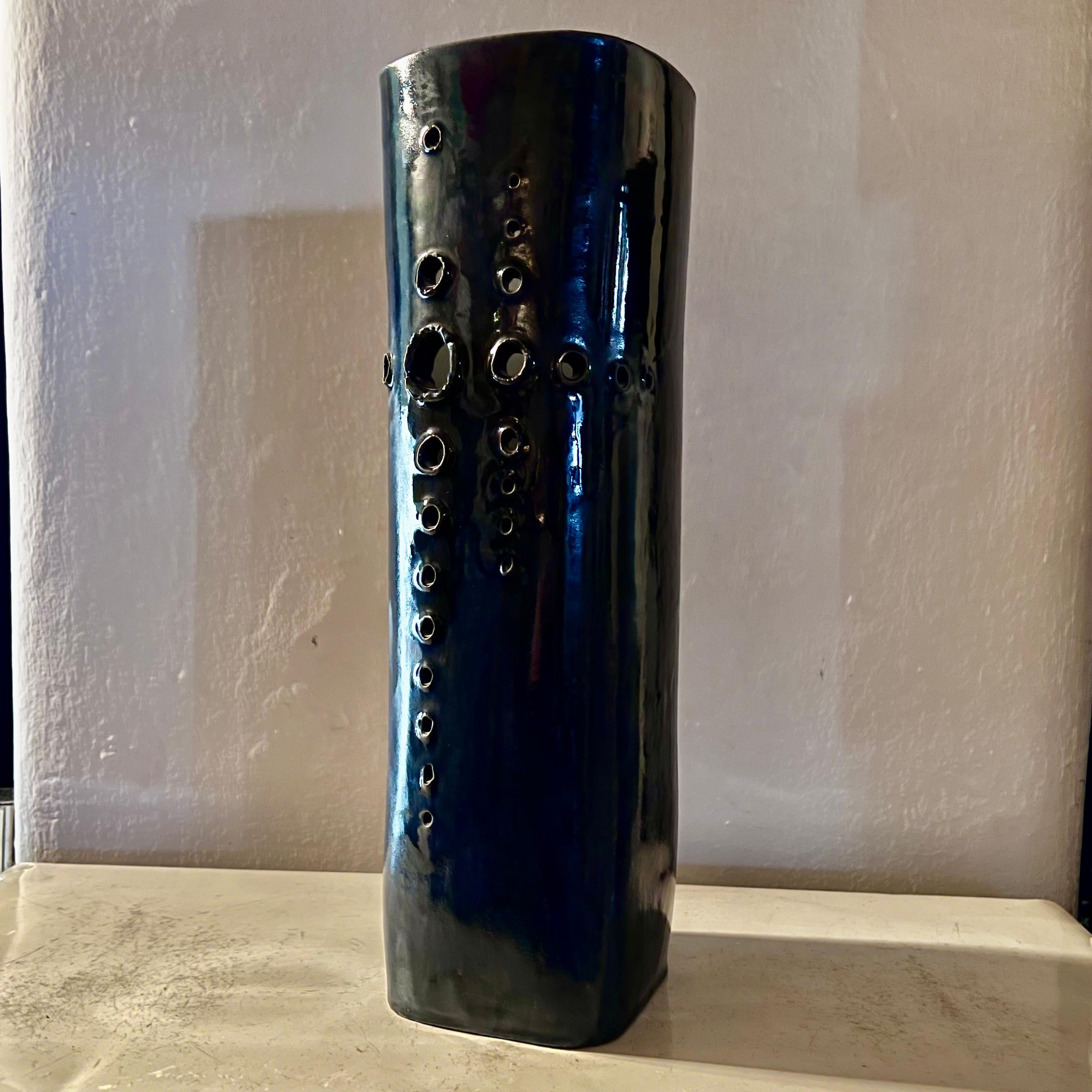 Large vase handmade of thick ceramic, painted in an intense blue, externally and white, internally.
The cross section of the vase is square with rounded corners. 
On one side it has a decoration composed of a series of holes of various gauges, made