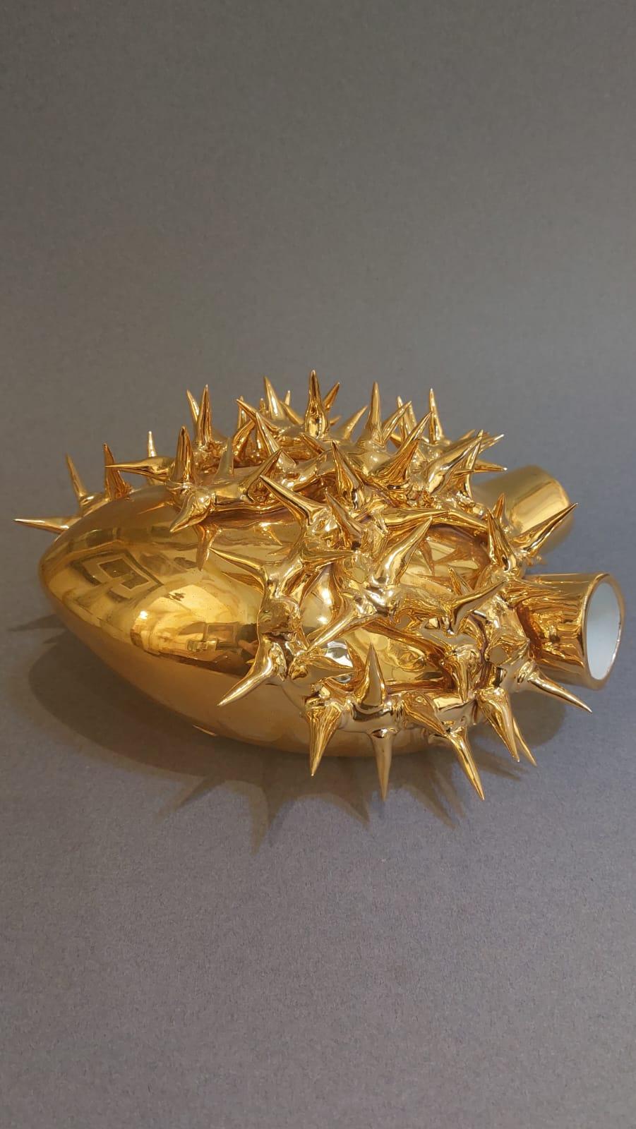 The vase with heart-shaped design was made of ceramic and then gilded. It has great decorative value but also a practical function, as it has two holes that can hold flowers.

As can be seen from the engraved marks, the production is made in Italy,