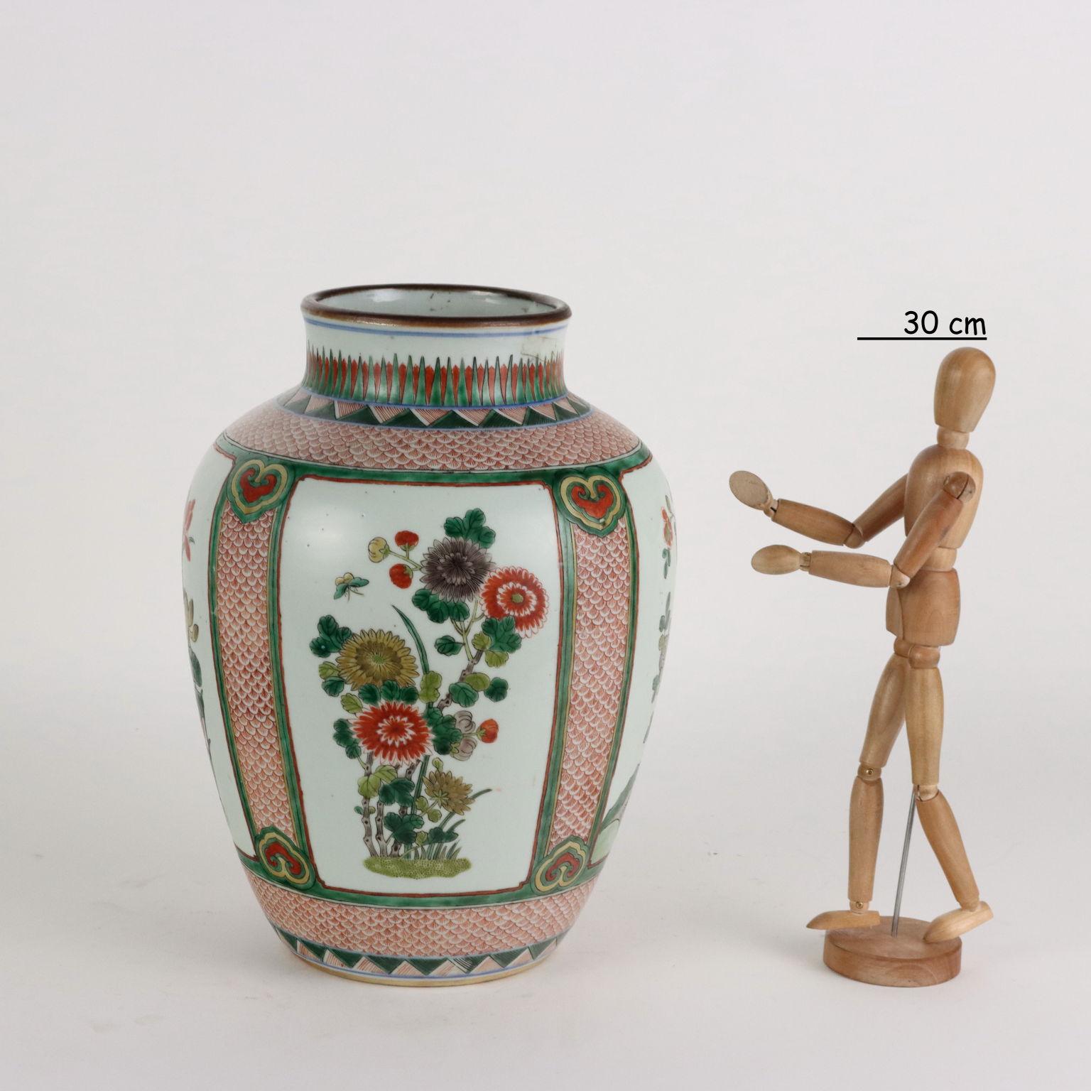 Vaso in porcellana dipinto a smalti wucai entro riserve con decoro di piante di crisantemo e peonie su un fittissimo sfondo con motivo a squame di pesce dipinto in rosso. Oggetto in buone condizioni, presenta piccoli segni di usura. Cerchiamo di