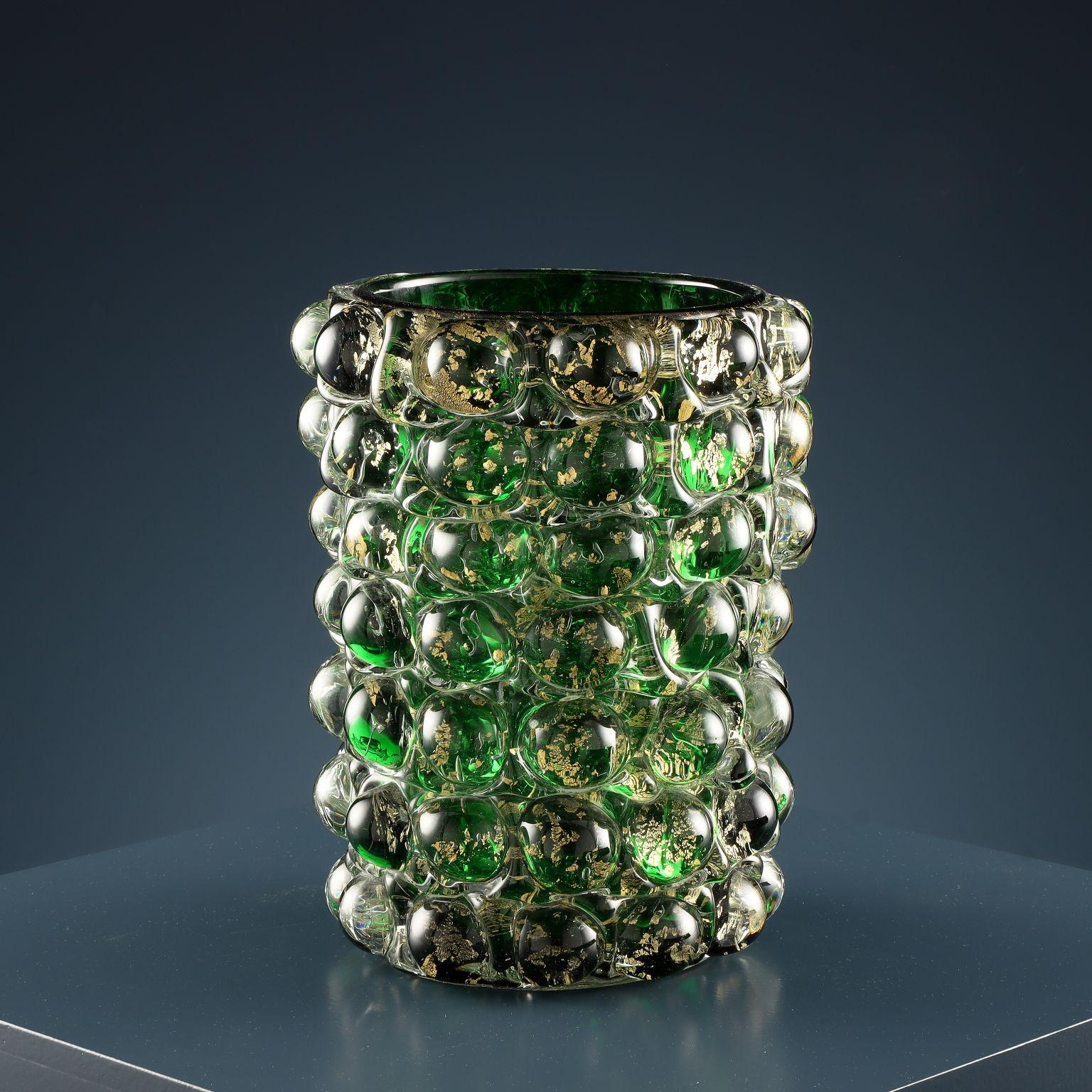 Vaso cilindrico in vetro di Murano verde e foglia d’oro con decoro di emisfere ottenute a stampo.
Disegnato da Ercole Barovier per una produzione Barovier & Toso, serie ‘Lenti’.