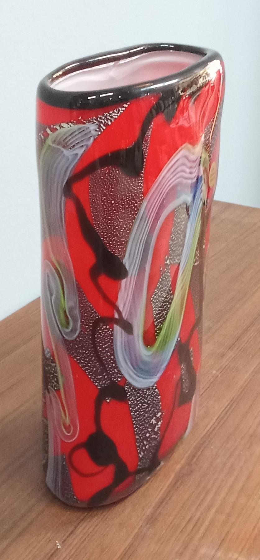 Ein wunderschönes rotes Glas mit mehrfarbigen, nero, verde, bianco und celeste Motiven, das mit einem Silberpoliermittel eine eindrucksvolle Textur aus Formen und Farben erzeugt.
Vaso in vetro di Murano (Venedig). Anni '80 circa.