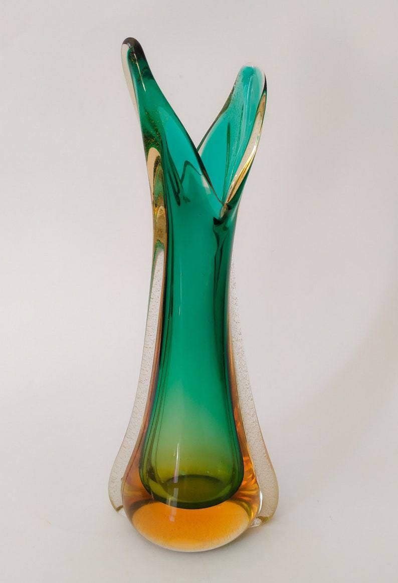 Unico nei suoi dettagli vaso sommerso Flavio poli per Seguso.
Color ambra chiaro-scuro.
Color verde chiaro-scuro.
Un mix di emozioni nel guardare questi colori che danno vita ad un vaso scultura del 1950.
Annodato a mano lavorato nei periodi dei