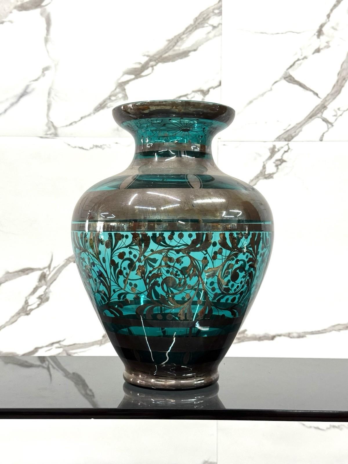 VASO IN VETRO E ARGENTO OVERLAY – AMERICAN ART DÉCO, ANNI ’30

Raro esempio di maestria artigianale americana degli anni ’30, questo vaso è realizzato in vetro soffiato con overlay in argento sterling finemente inciso. Il vetro presenta una vibrante