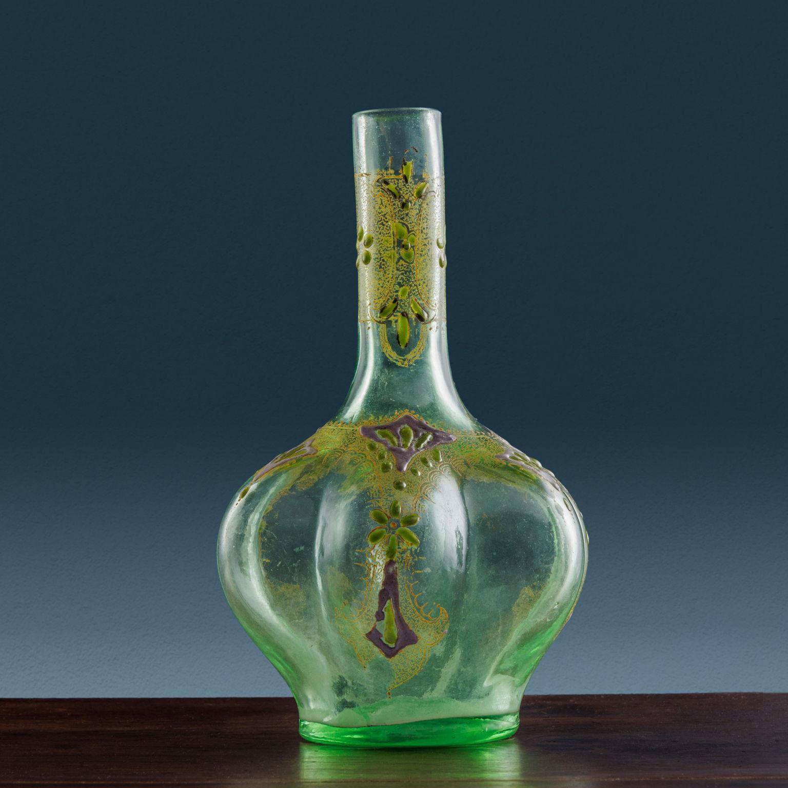 Green blown glass vase characterized by bulbous elements in the body molding, decorated with green, silver, and gold enamels present on both the body and neck of the vase. The enamels depict floral designs flanked by ornamental gold motifs of