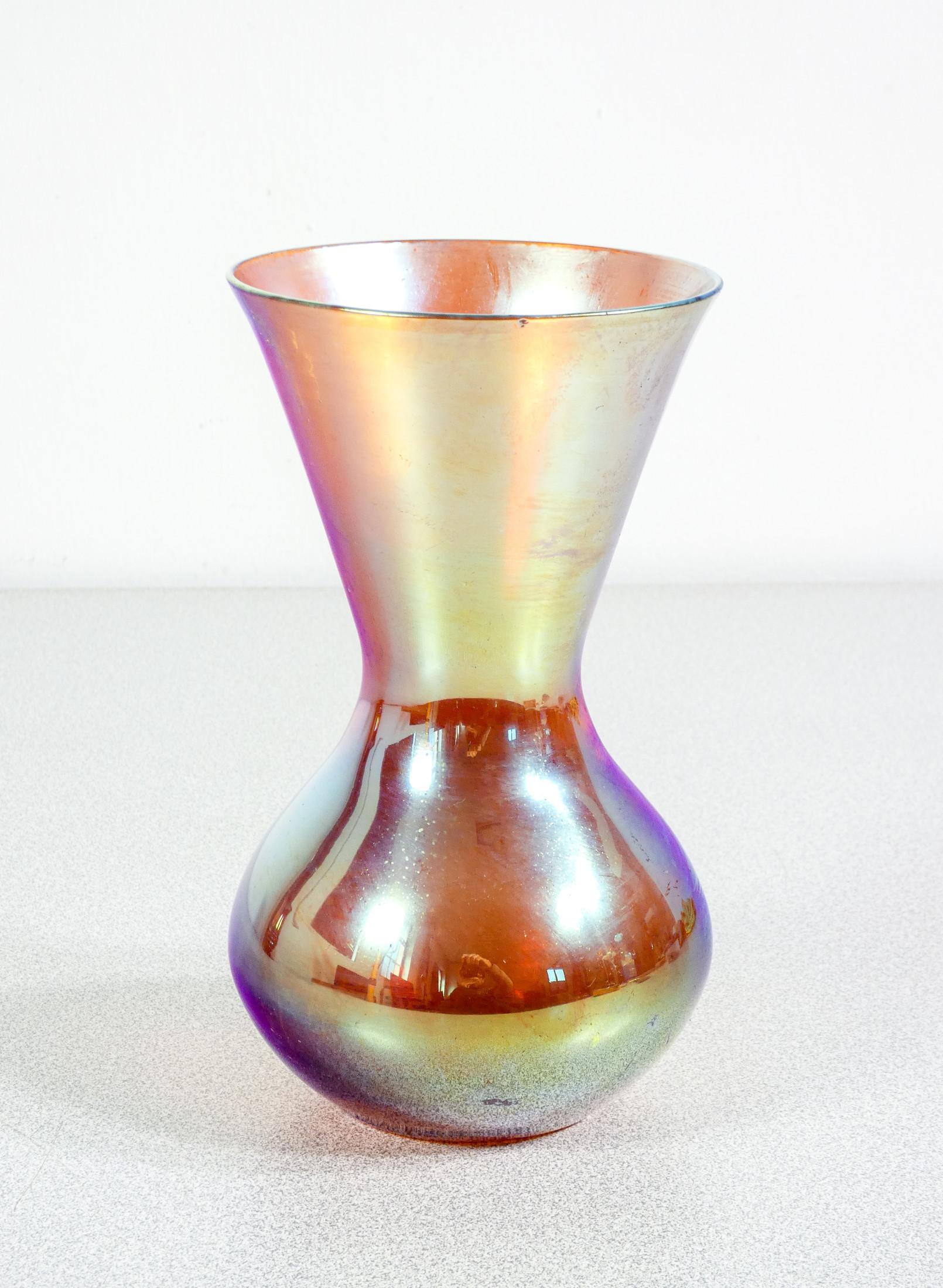 Vaso in vetro
soffiato iridescente
WMF serie Myra.

ORIGINE
Germania

PERIODO
Anni 20/30

MARCA
WMF

MODELLO
Serie Myra

MATERIALI
Vetro soffiato iridescente

DIMENSIONI
Altezza: 18 cm
Ø 10 cm

CONDIZIONI
Il vaso è in ottime condizioni, come è
