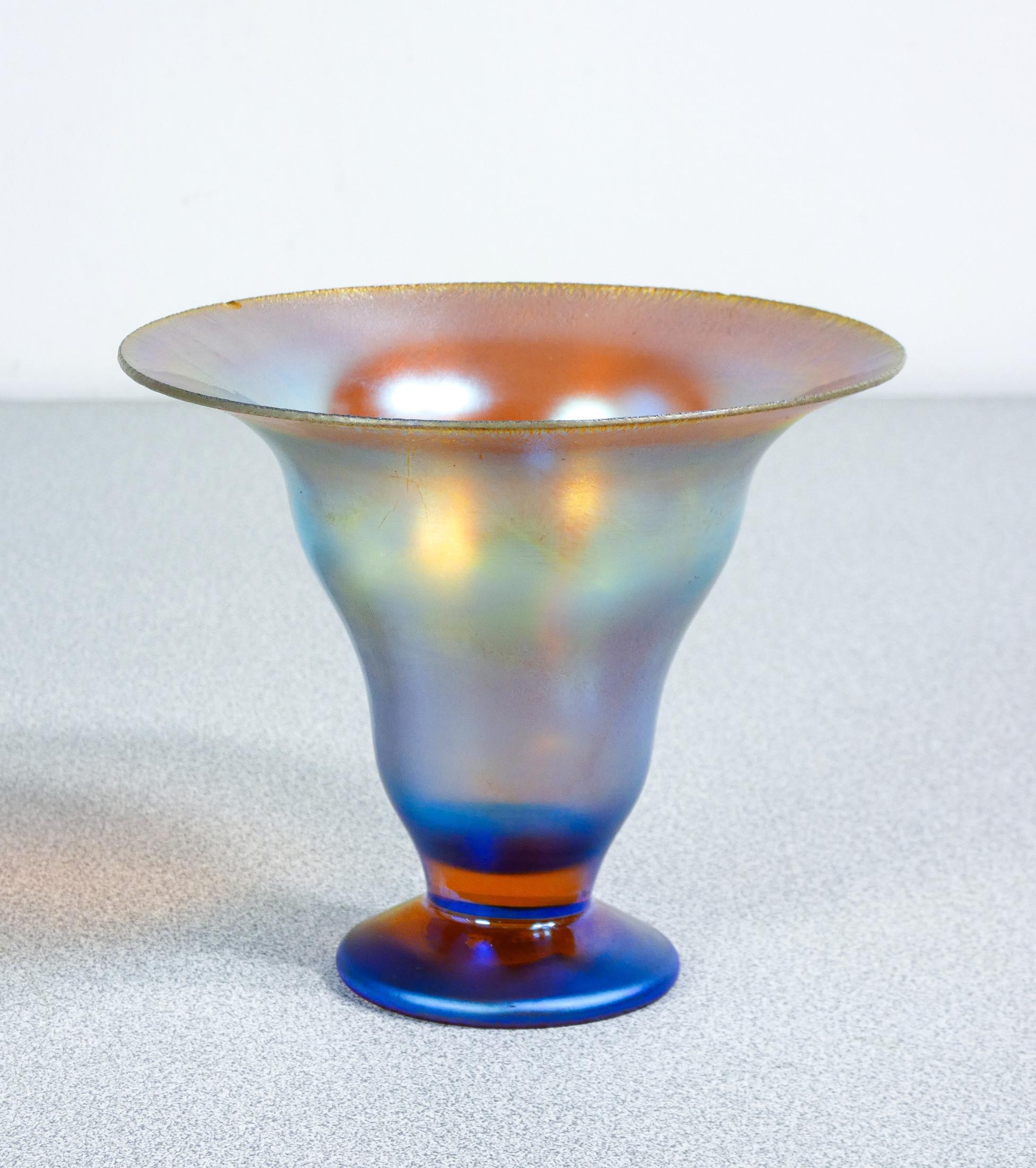 Jarrón, cuenco de cristal
soplado iridiscente
Serie WMF Myra.

ORIGEN
Alemania

PERÍODO
Años 20/30

MARK
WMF

MODELO
Serie Myra

MATERIALES
Vidrio soplado iridiscente

DIMENSIONES
Altura: 11 cm
Ø 13 cm

CONDICIONES
El jarrón está en excelentes