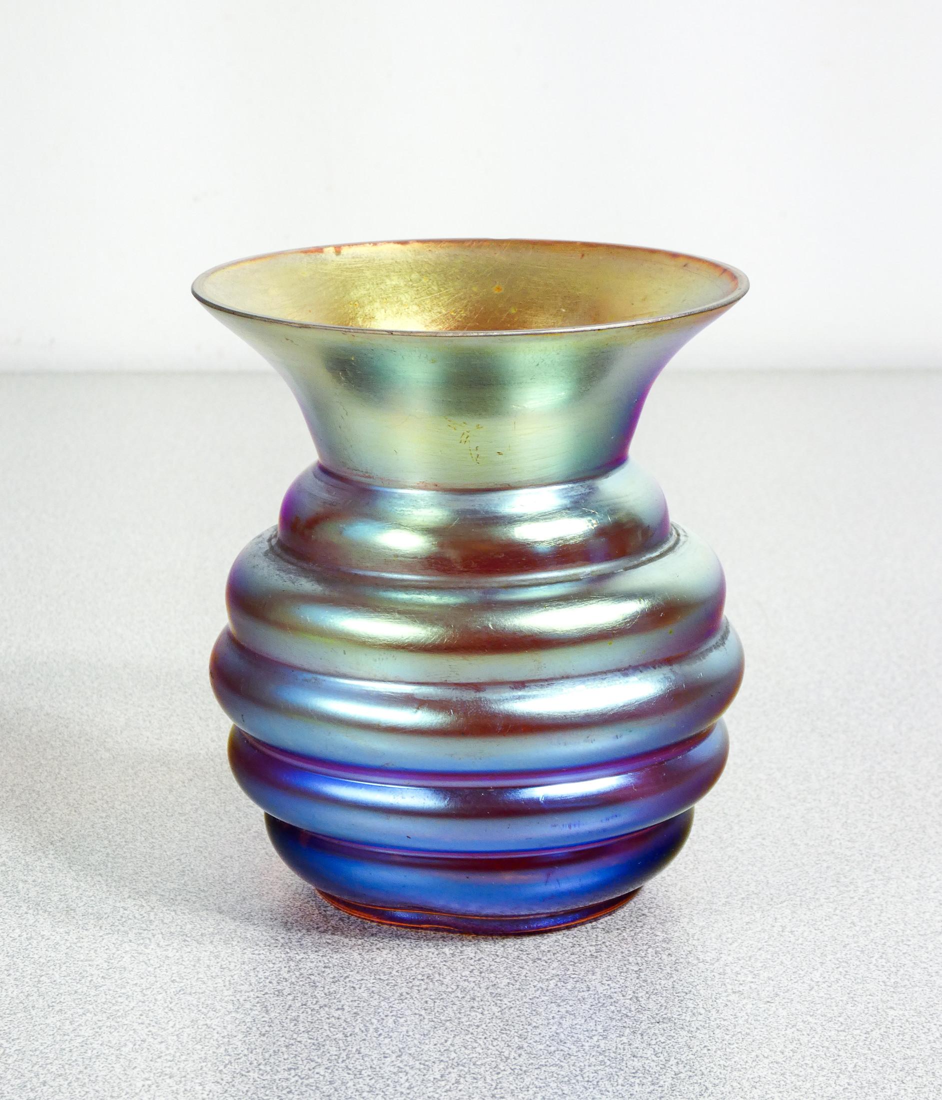 Vaso in vetro
soffiato iridescente
WMF serie Myra.

ORIGINE
Germania

PERIODO
Anni 20/30

MARCA
WMF

MODELLO
Serie Myra

MATERIALI
Vetro soffiato iridescente

DIMENSIONI
Altezza: 11.5 cm
Ø 9.5 cm

CONDIZIONI
Il vaso è in ottime condizioni, come è