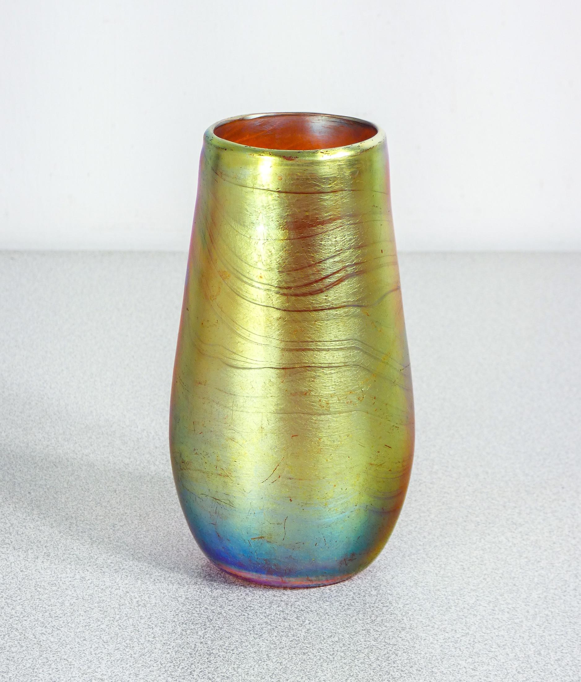 Glass jar
blown iridescent
WMF Myra series.

ORIGIN
Germany

PERIOD
Years 20/30

MARK
WMF

MODEL
Myra Series

MATERIALS
Iridescent blown glass

DIMENSIONS
Height: 13.5cm
Ø 7.5 cm

CONDITIONS
The jar is in excellent condition, as can be seen from the
