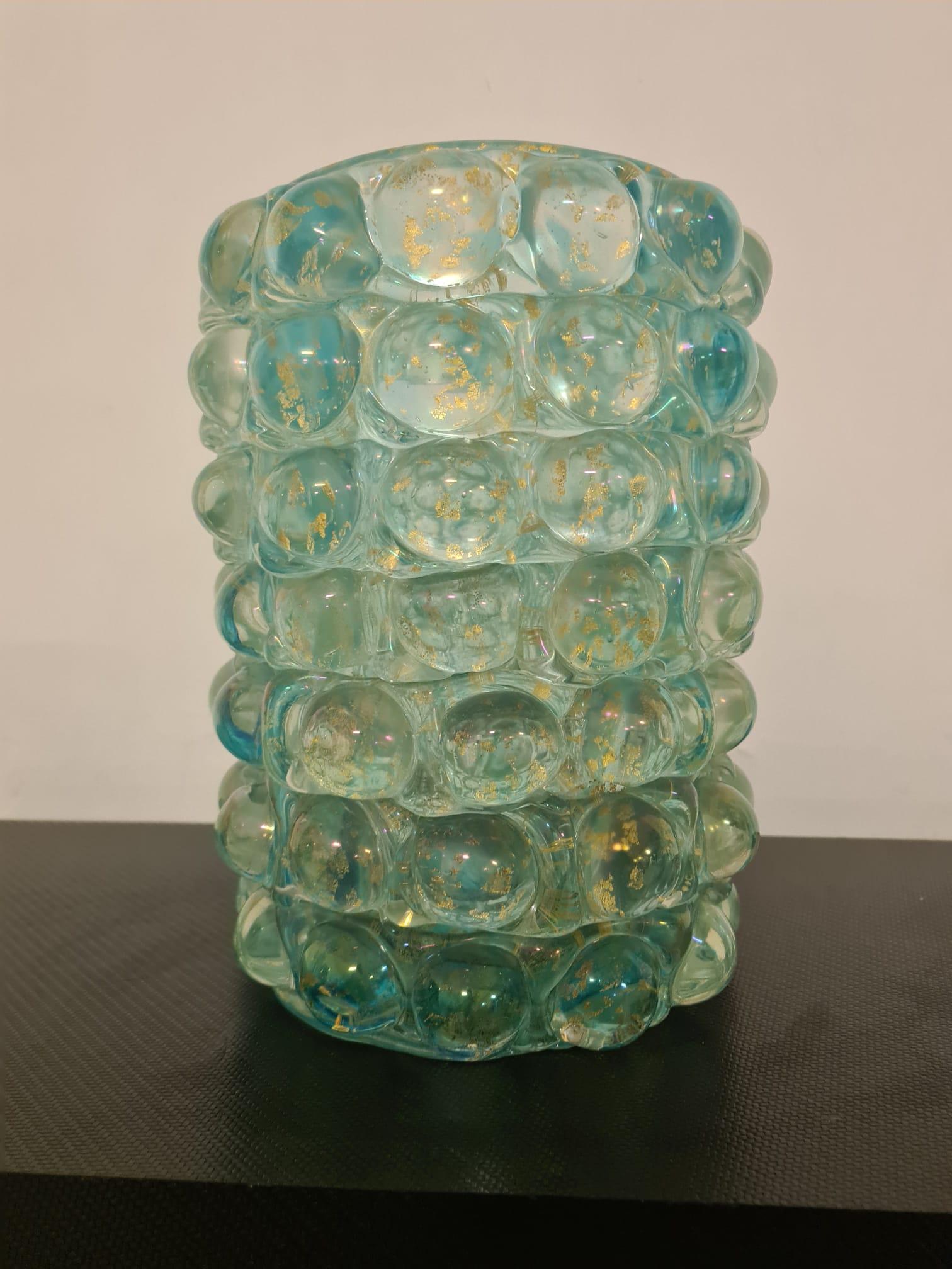 Vaso lenti Ercole Barovier.

Elegante vaso della serie Lenti in vetro sommerso.

Color acquamarina con inclusioni a foglia d'oro.

La superfice è trasparente ed è ricoperta da semisfere appunto delle lenti.

La serie lenti è stata prodotta negli