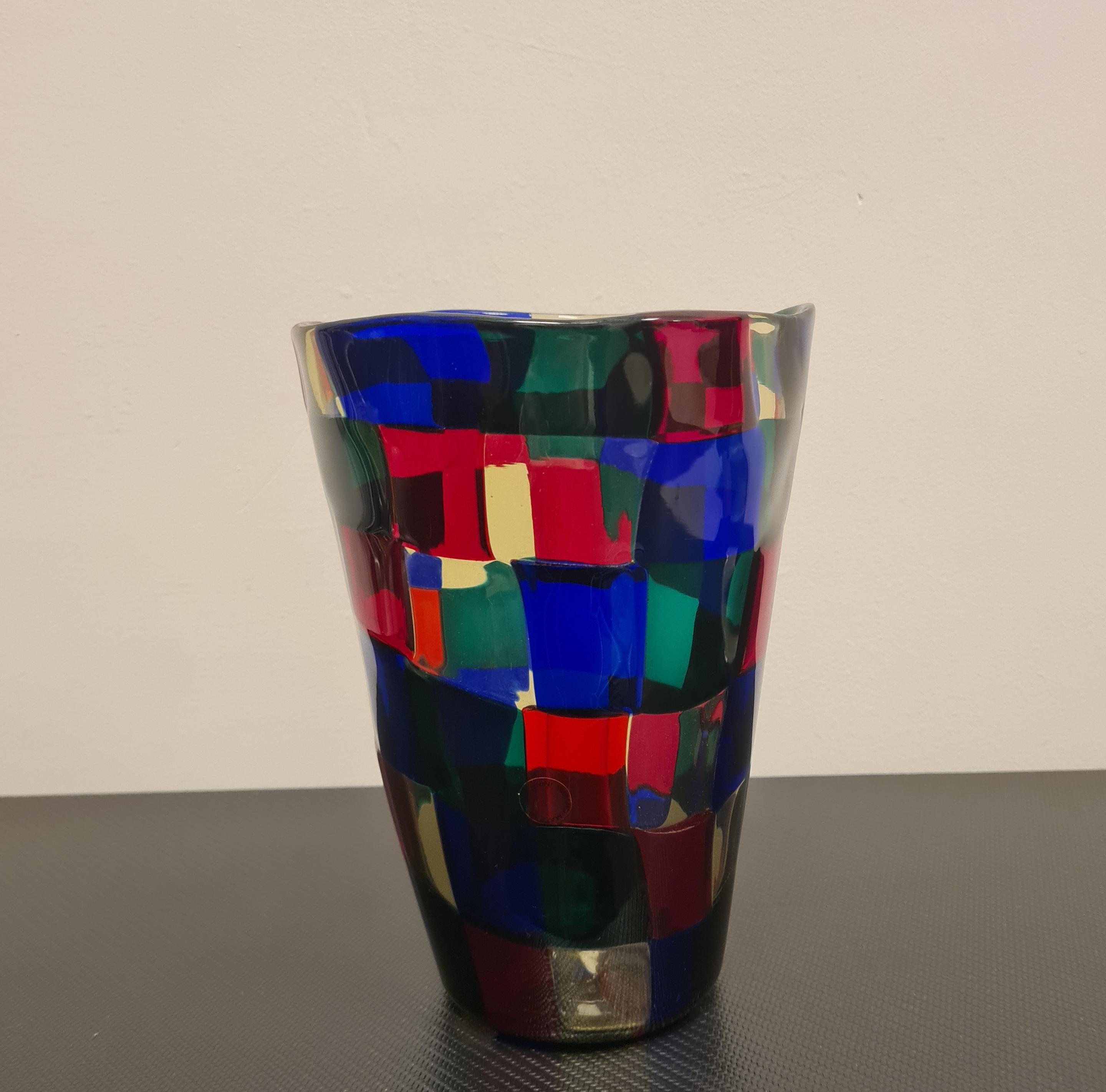 Vase from the Pezzati series designed by Fulvio Bianconi for Venini.

In Murano glass made with transparent glass tesserae in the colors pagliesco, red, sapphire and green.

Pezzati was presented at the XXV Venice Biennale in 1950 where it was a