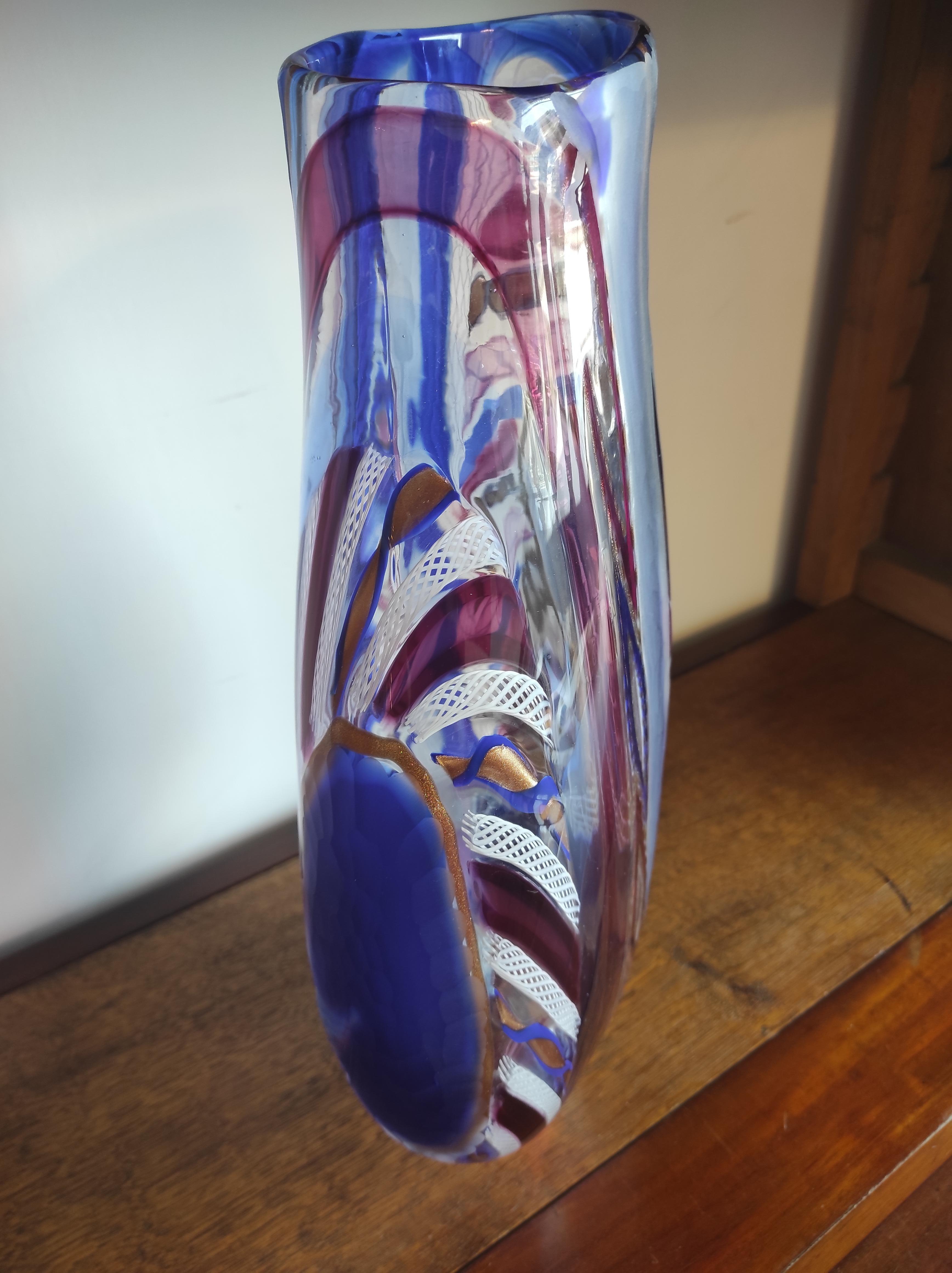 This Murano blown glass vase was created by Vetreria d' Este e Zane of Murano.
Different types of workmanship are present in this vase:
Lattice work: a technique that uses the reeds of  clear glass (glass rods) containing inside straight or
