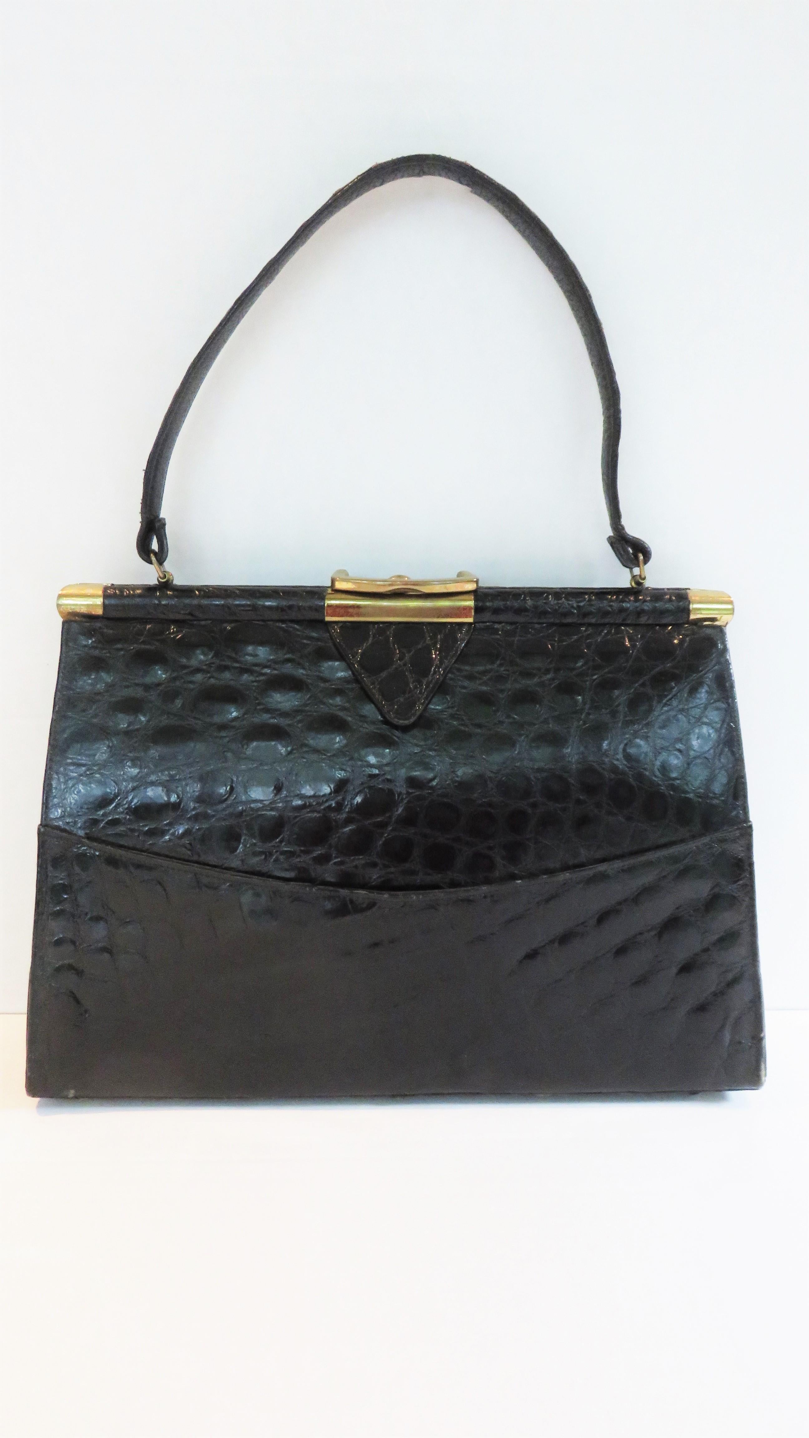 A gorgeous rich black alligator handbag by Vassar.  It has a top strap handle, a gold clasp and gold frame.  The inside is lined in black leather and has 4 inner pockets, one snaps closed, one zipper closes plus a matching leather change purse.