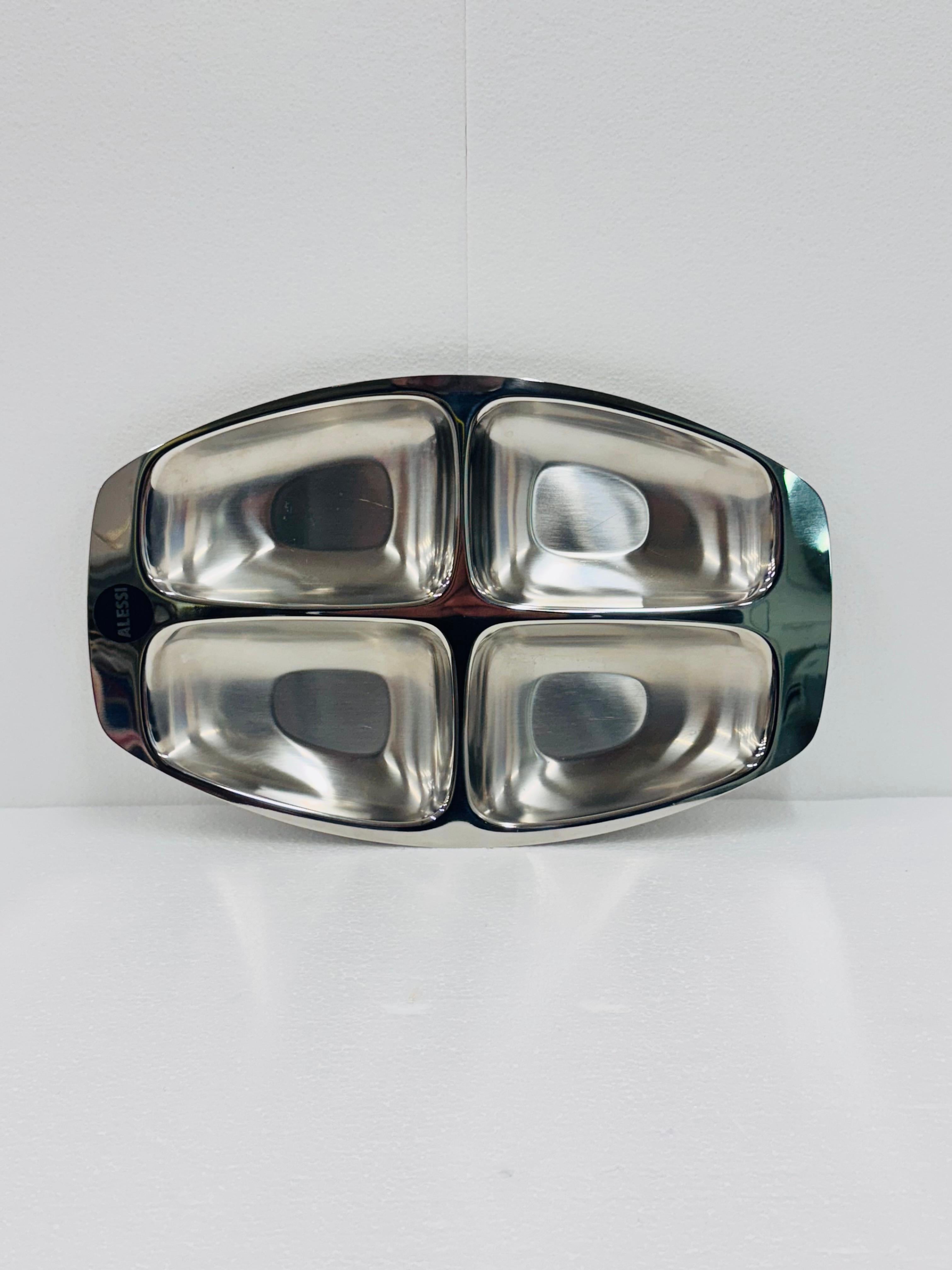 Bandeja de servicio, entremeses,  fabricado por Alessi en acero inoxidable 18/10

Forma parte de la exitosa serie de vajillas y utensilios de bar diseñados a partir de los años 70 por Carlo Mazzeri (a menudo en colaboración con Anselmo Vitale) 

El