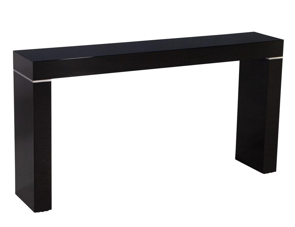 Vaughan Benz style ebonized console table with silver trim. America, circa 1970’s. Sleek modern styling with silver trim accents. Newly restored in a high gloss polished black lacquer. Price includes complimentary curb side delivery to the