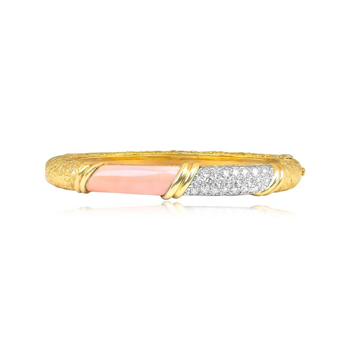 A stunning vintage Van Cleef & Arpels bangle, circa the 1970s, showcases a segment of angel skin coral and pave-set diamonds, with a textured gold design. This 18k yellow gold bangle, signed VCA and crafted in France, exudes timeless elegance.
The