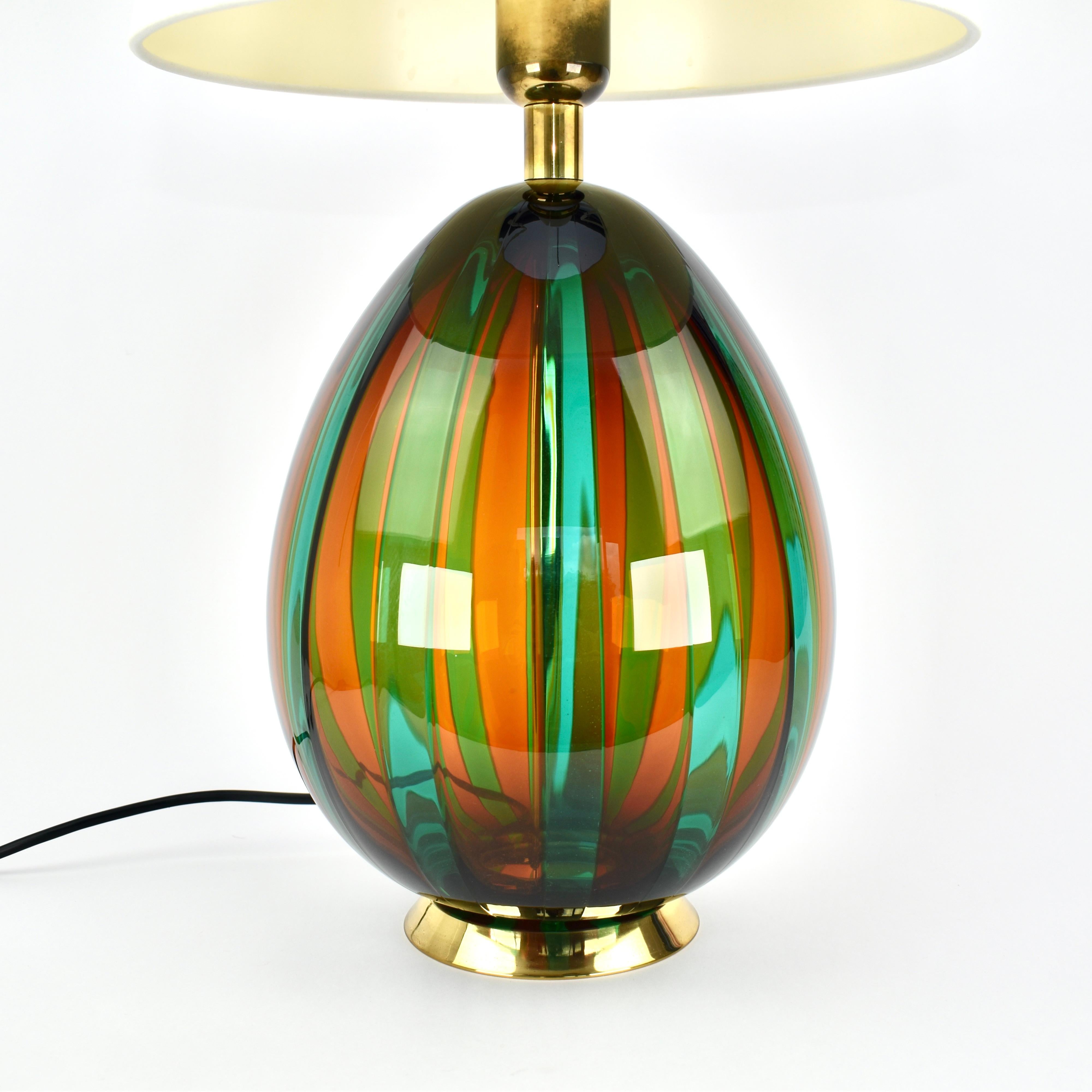 A striking vintage Murano glass table lamp by VeArt, featuring rich green, red striped glass with elegant brass accents. Handcrafted in Italy, this piece reflects the artistry of Murano glassmakers, blending Mid-Century Modern style with Hollywood
