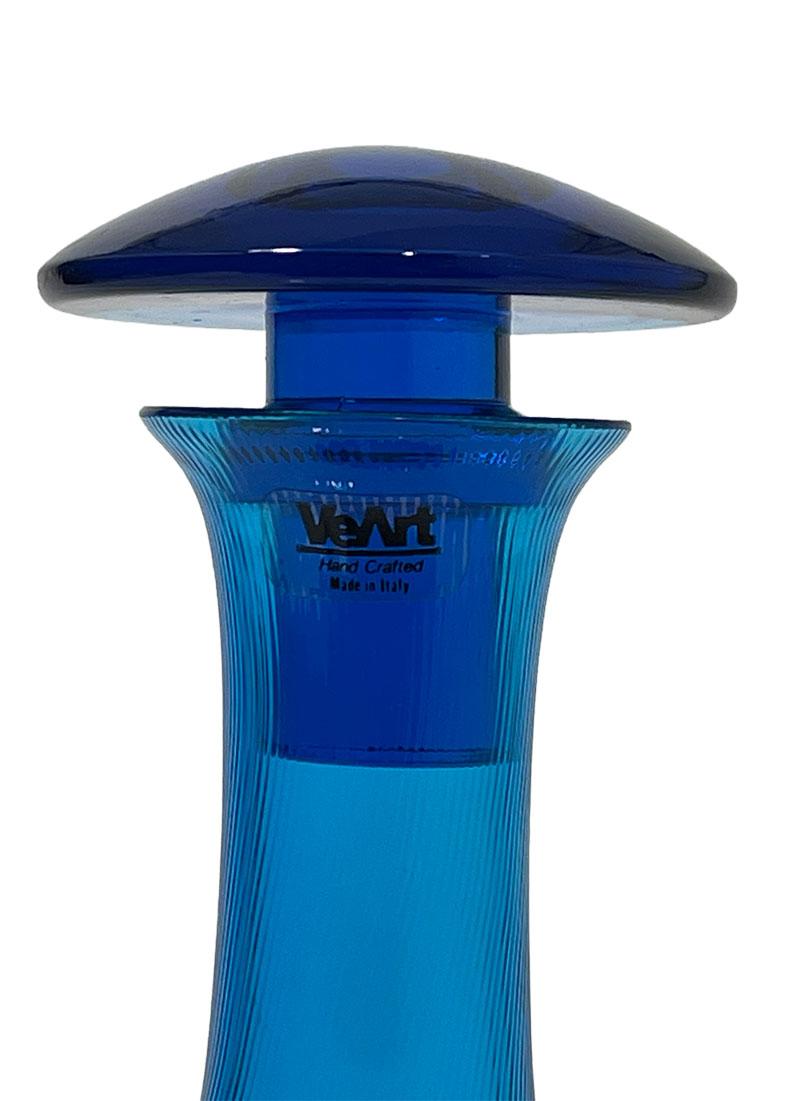 Veart Vetreria, Italian blue glass decanter, 1980s

A blue carafe/ decanter, made of glass with a swirl pattern. Made in Italy, in the 1980s. Signed on the bottom with etched name Veart Vetreria and a sticker on the neck of the bottle. 
The