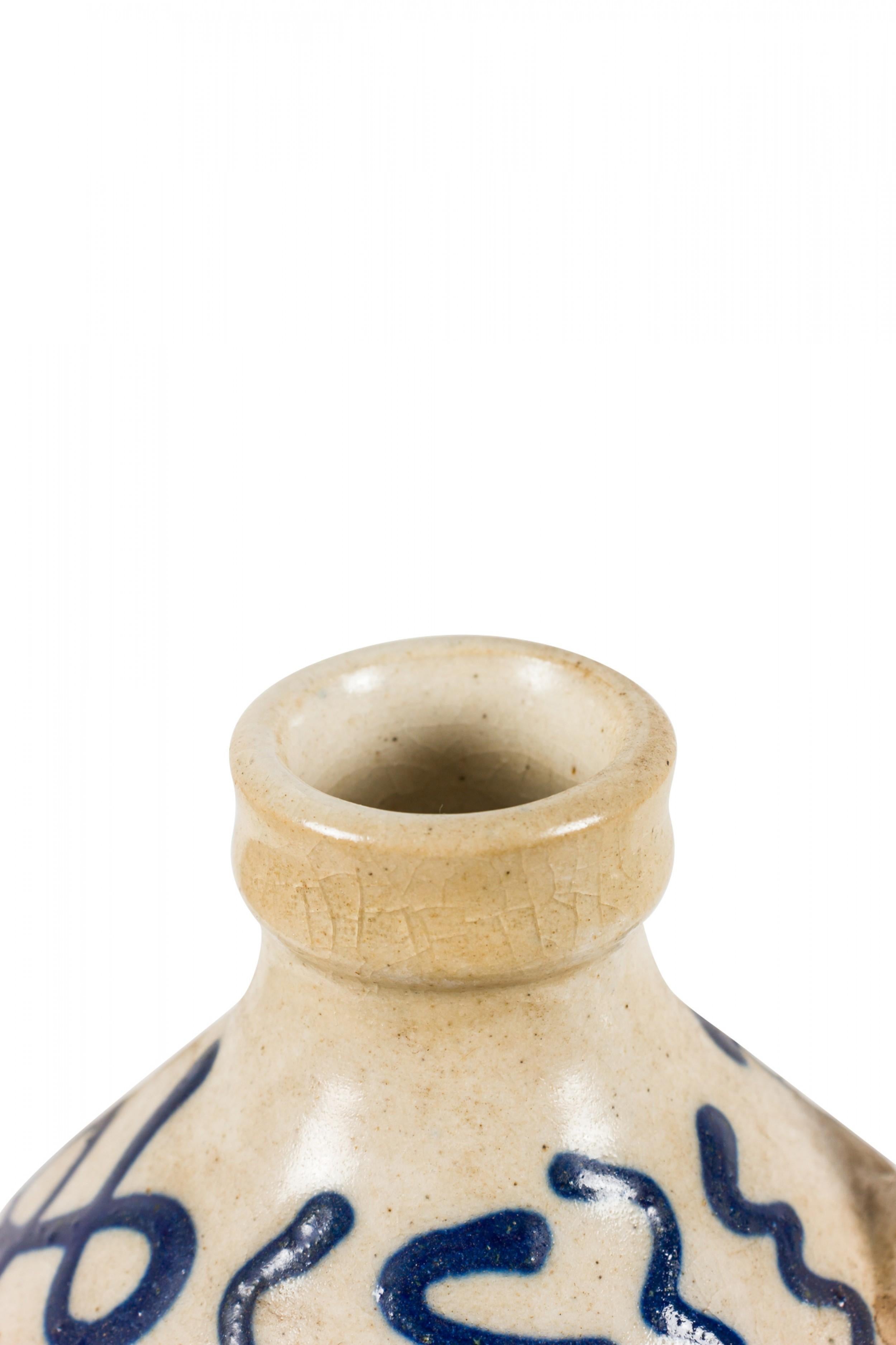 East German Mid-Century ceramic bottle vase with a geometric and sunburst pattern in dark blue against a cream-colored glazed ground with a small handle. (Bischofswerdaer Braun & Kunsttöpferei, mark and label on bottom, B BTK 11/2).