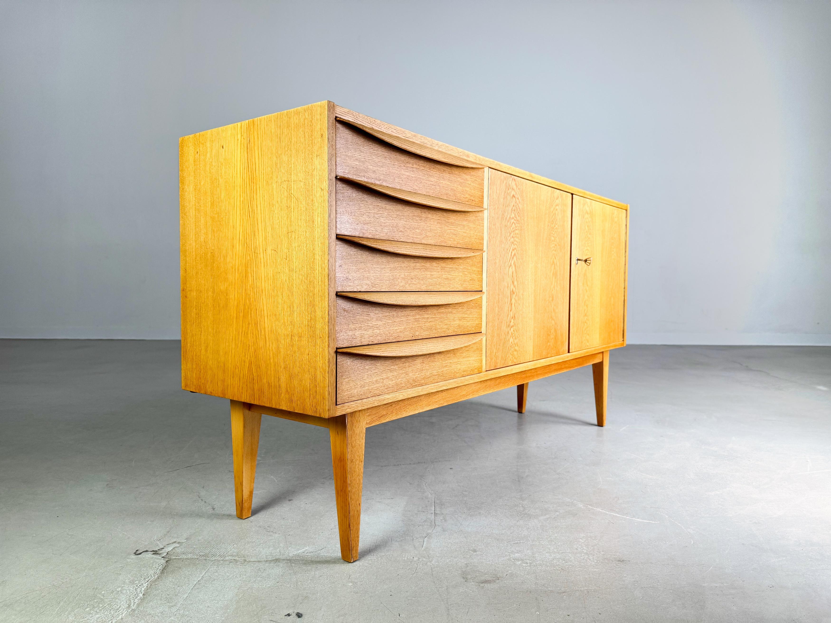 Wir bieten ein wunderschönes Sideboard von VEB DW Hellerau aus der beliebten Serie 602 zum Verkauf an. Le Design/One est l'œuvre du maître d'œuvre Franz Ehrlich, connu pour ses lignes claires et ses objets fonctionnels, et qui se distingue par sa
