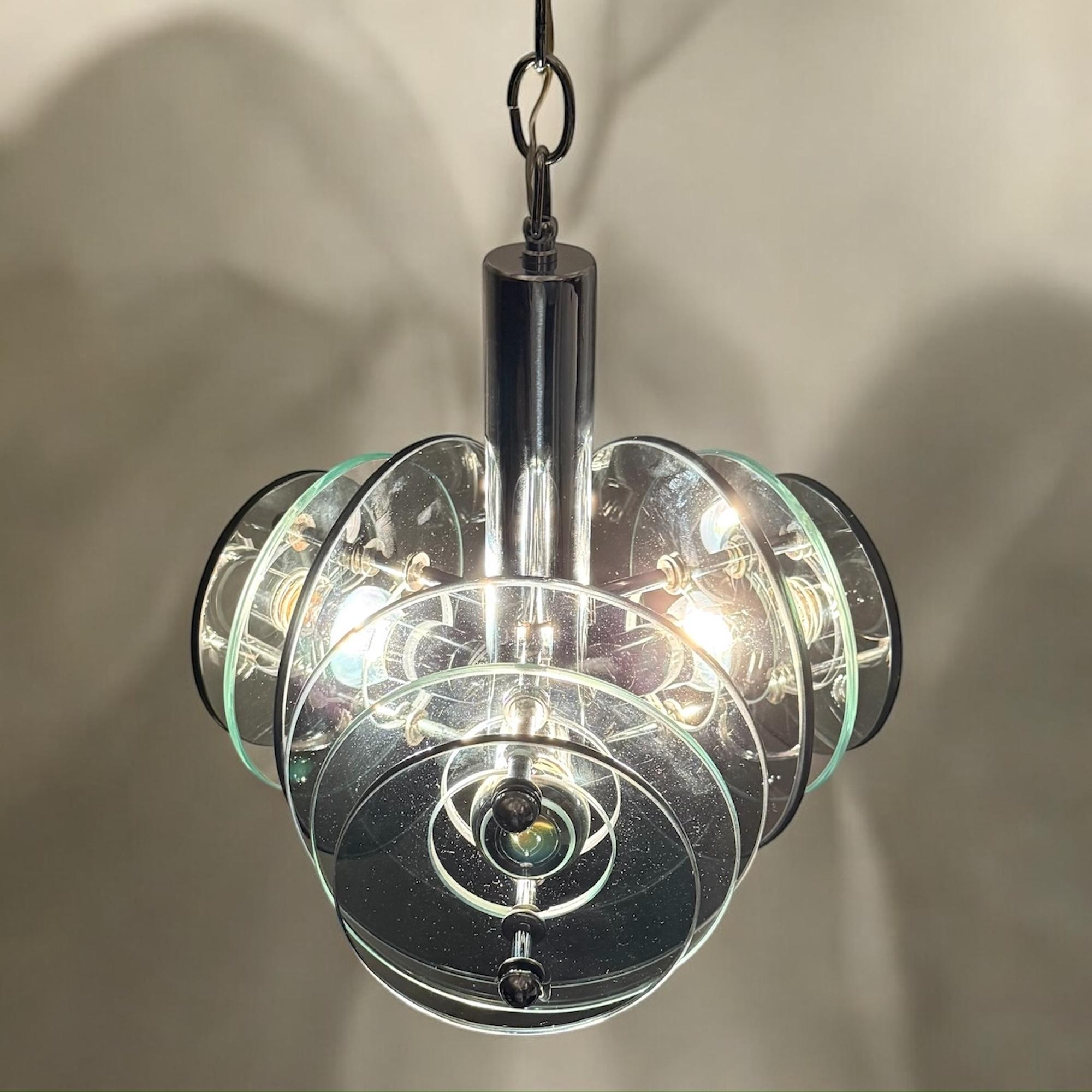 Stupenda lampada Space AGE di Veca, una vera e propria icona del design italiano degli anni '70. Caratterizzata da un'elegante struttura in metallo cromato, questa lampada a sospensione vanta una disposizione futuristica di dischi di vetro fumé e