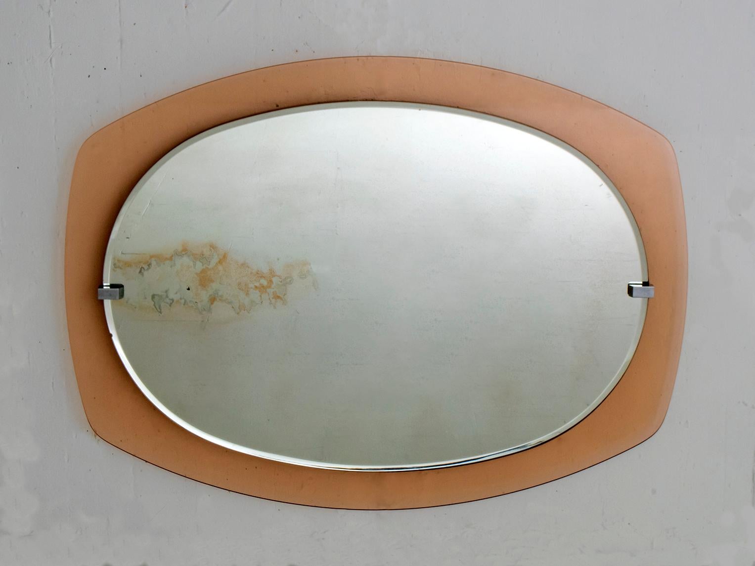 Ce miroir biseauté a été produit dans les années 1960 par la célèbre entreprise italienne Veca. Elle présente un cadre en verre caramélisé et des têtes de vis en laiton nickelé.