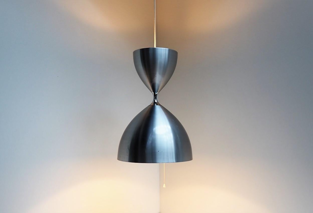 Impressive pendant in brushed aluminium with a chrome middle piece called Vega is designed by Jo Hammerborg for Fog & Mørup in the 1960s.

The diabolo shape is very cool as well different and the pendant is one of the most iconic designs from Jo