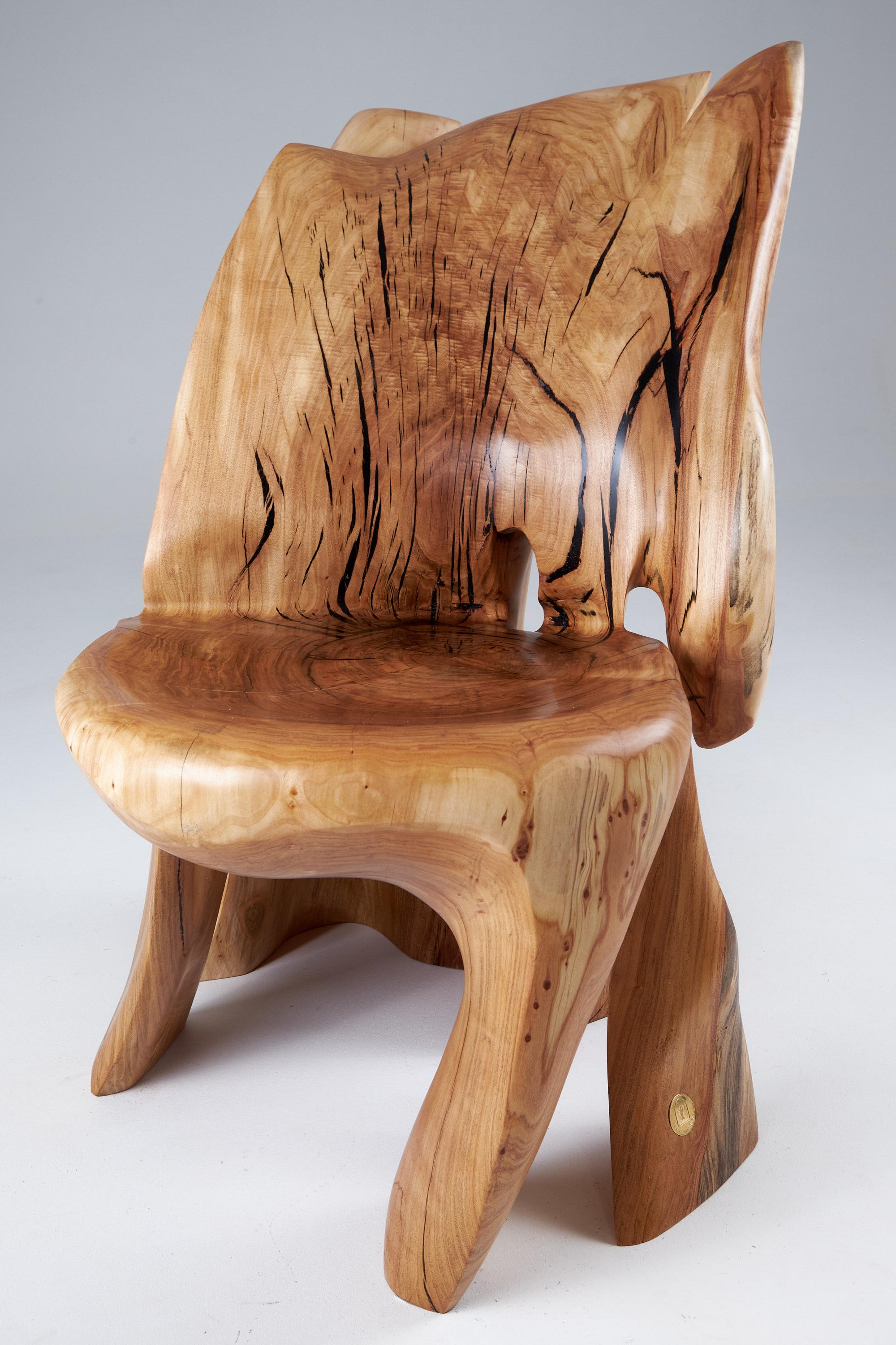Unique functional sculpture carved from a single piece of wood in the shape of an lounge chair. Each piece in our production is carved by artists with basic wood carving power tools. Every chair is made as unique as it can be, with dedication to