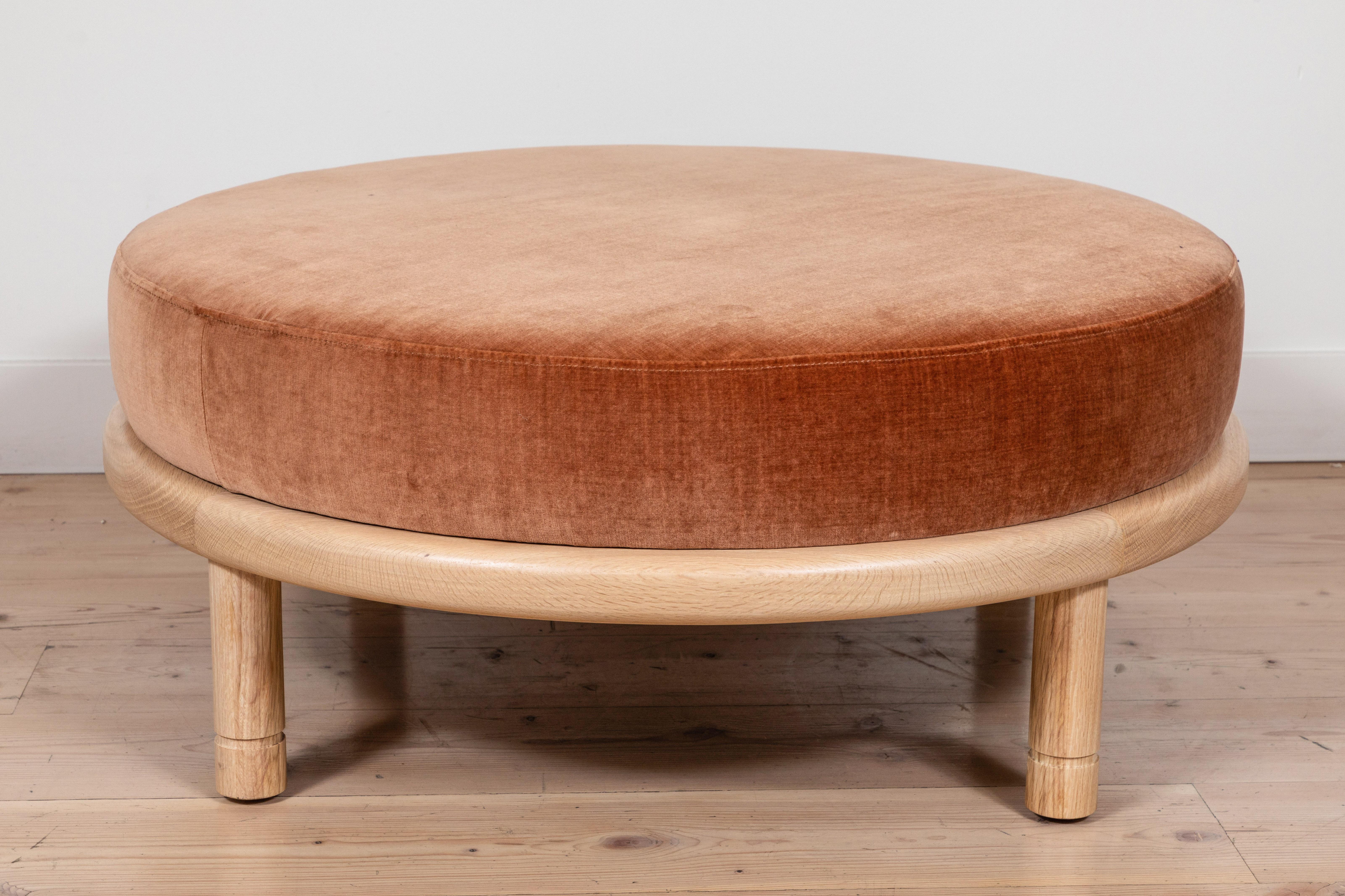 The Moreno Ottoman features a round solid wood base with four cylindrical legs and an upholstered top. Available in American walnut or white oak. Shown here in natural oak. Shown here in coral velvet and natural oak. 

The Lawson-Fenning