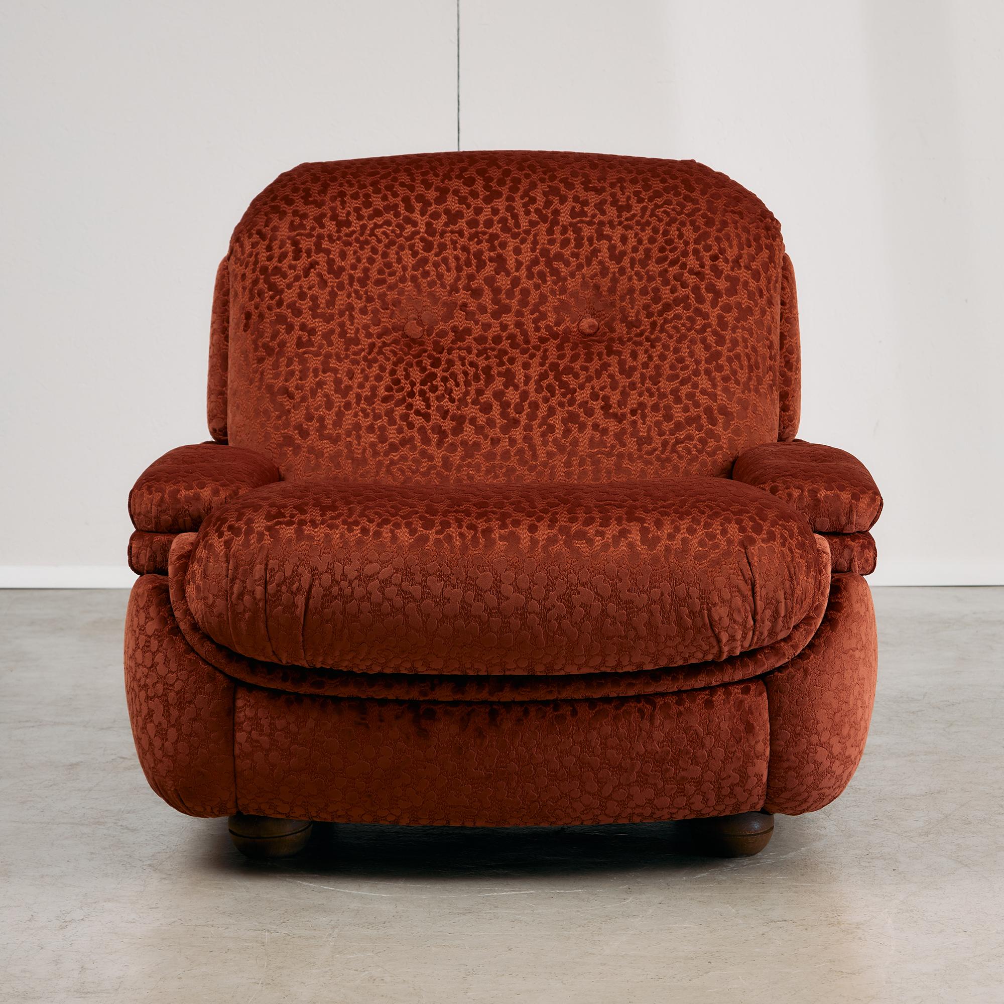 Crafted in the 1970s and recently reupholstered, this armchair is a bold study in texture, tone, and form. The burnt velvet fabric creates a dynamic visual effect, shifting between red clay and oxblood hues depending on the light and angle — lending