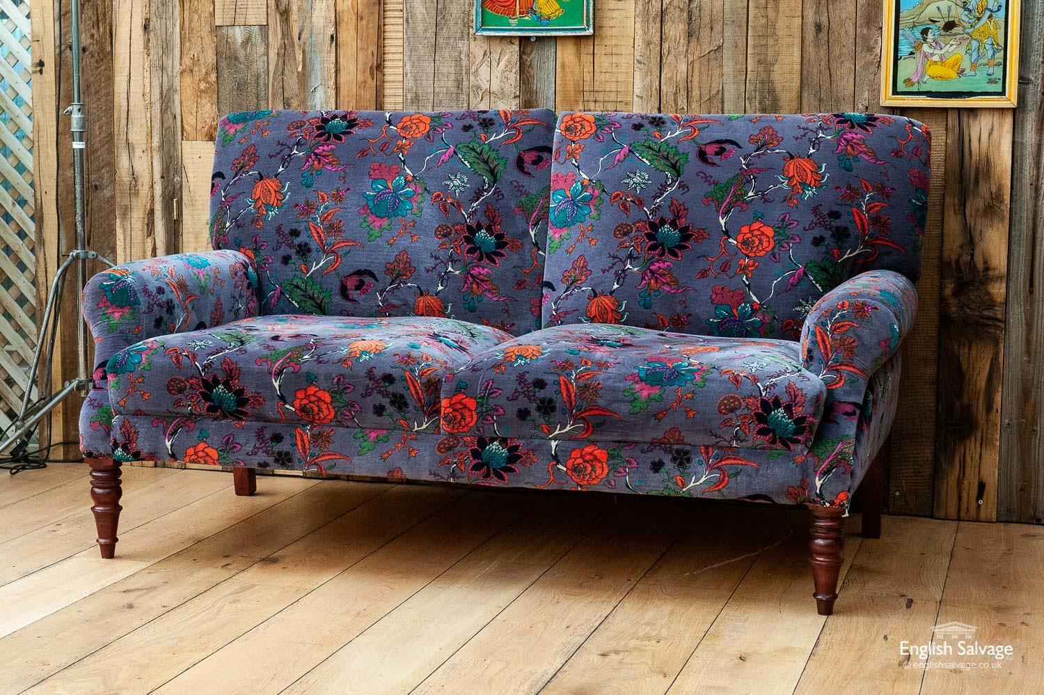 Newly made traditional club style sofas, two-seat, each with turned wooden feet and upholstered in a vibrant floral patterned cotton velvet. The seat height is approximately 44cm. Made in India.