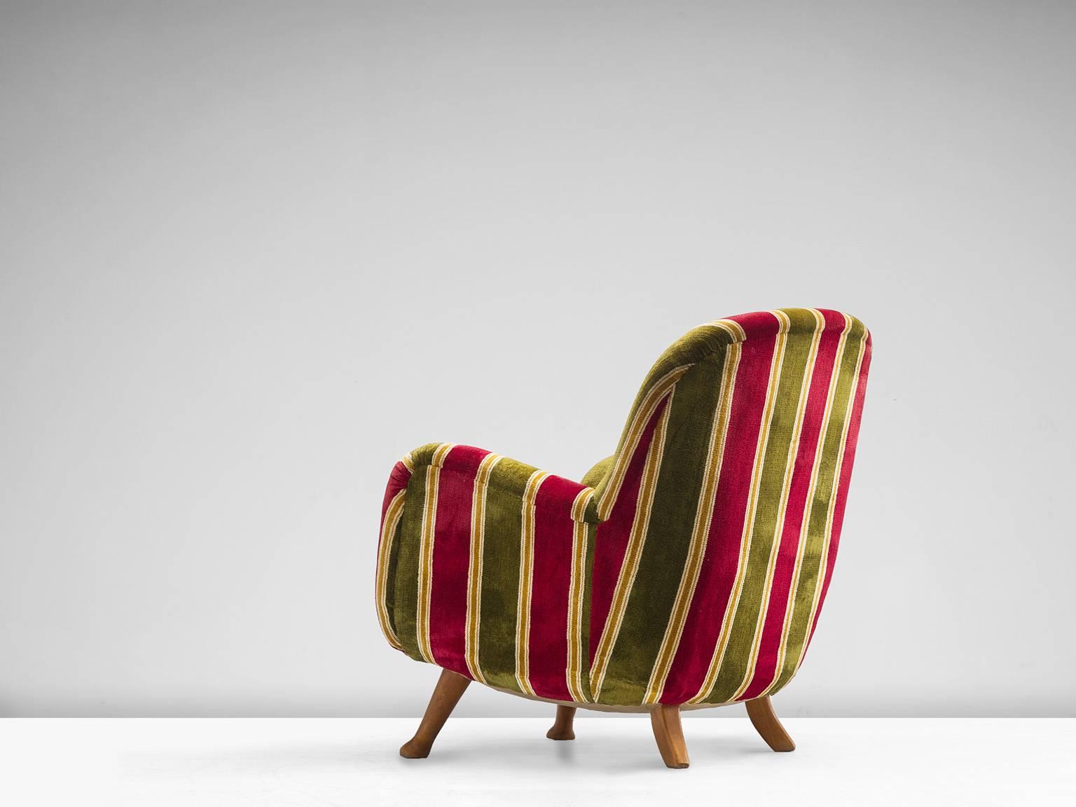 Armchair, green, red and ocre striped velvet and oak, Northen Europe, 1940s.

This colorful and curvy armchair is a very comfortable and strong singular item. The whole shell is slightly tilted backwards. The shell rests on four small oak legs that
