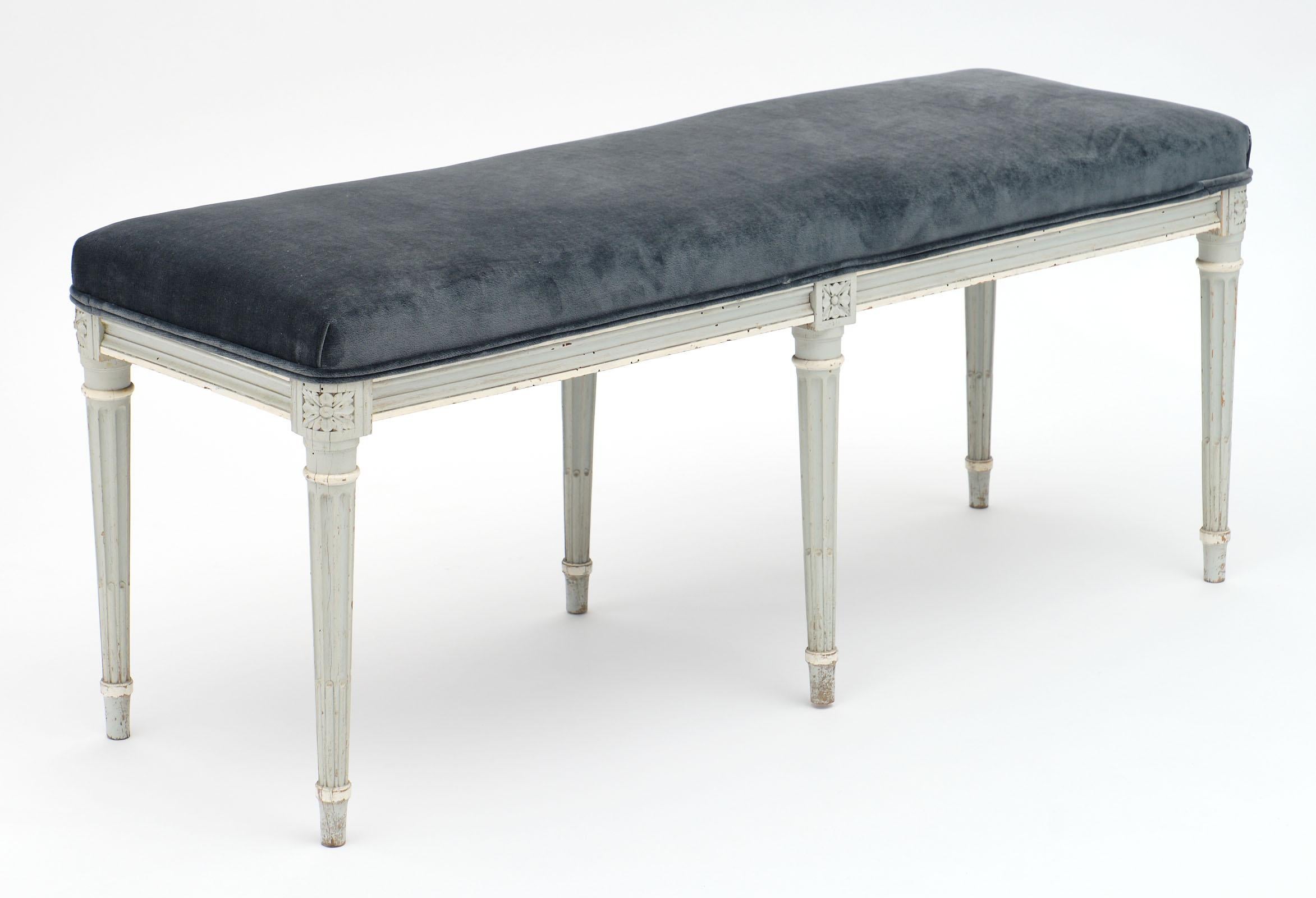 French antique Louis XVI style velvet piano bench made of painted beechwood. This piece has been newly upholstered in a blue gray velvet blend with double cording. The frame has hand carved legs and apron.
