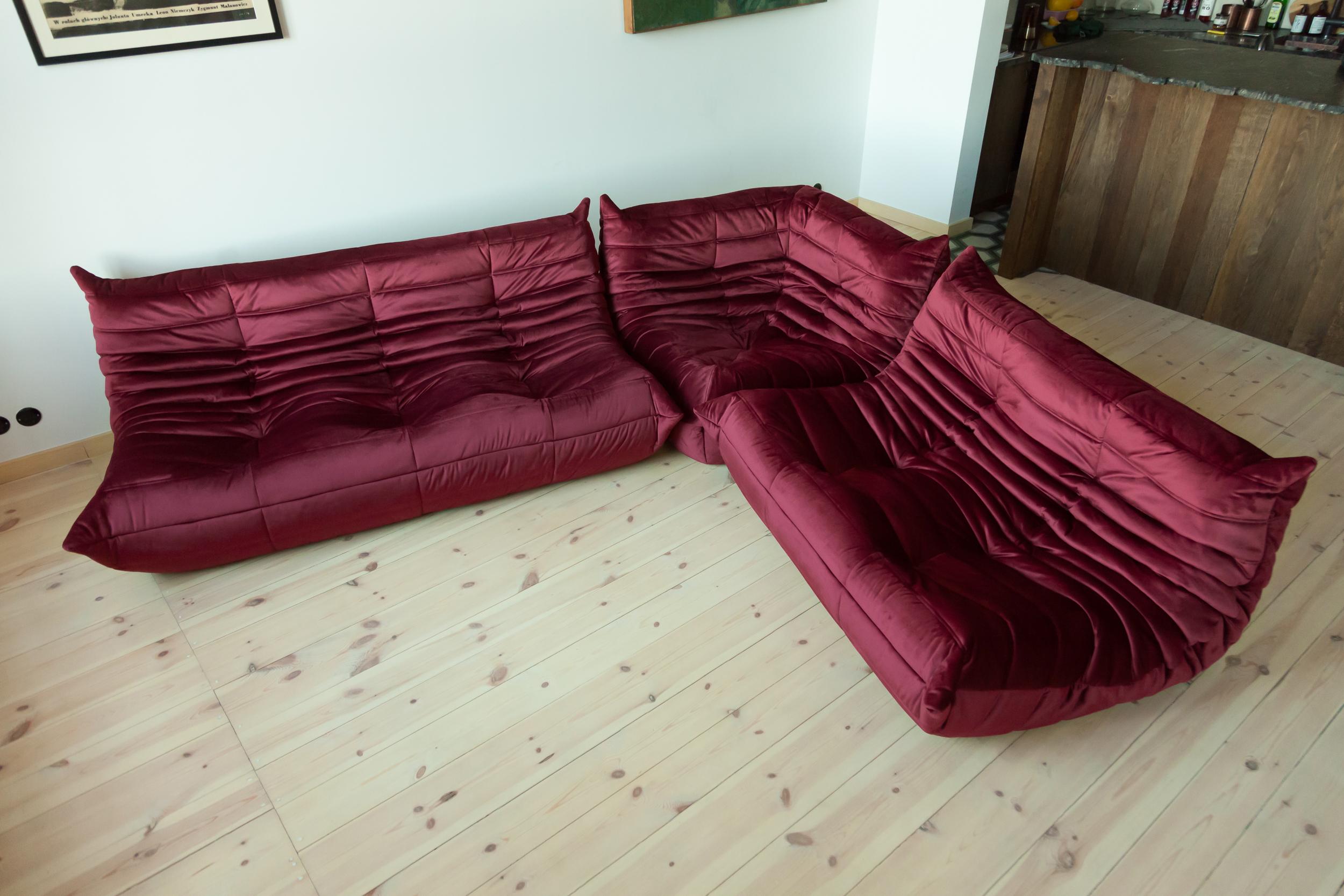 This Togo living room set was designed by Michel Ducaroy in 1973 and was manufactured by Ligne Roset in France. It has been reupholstered in high quality burgundy velvet and is made up of the following pieces, each with the original Ligne Roset logo