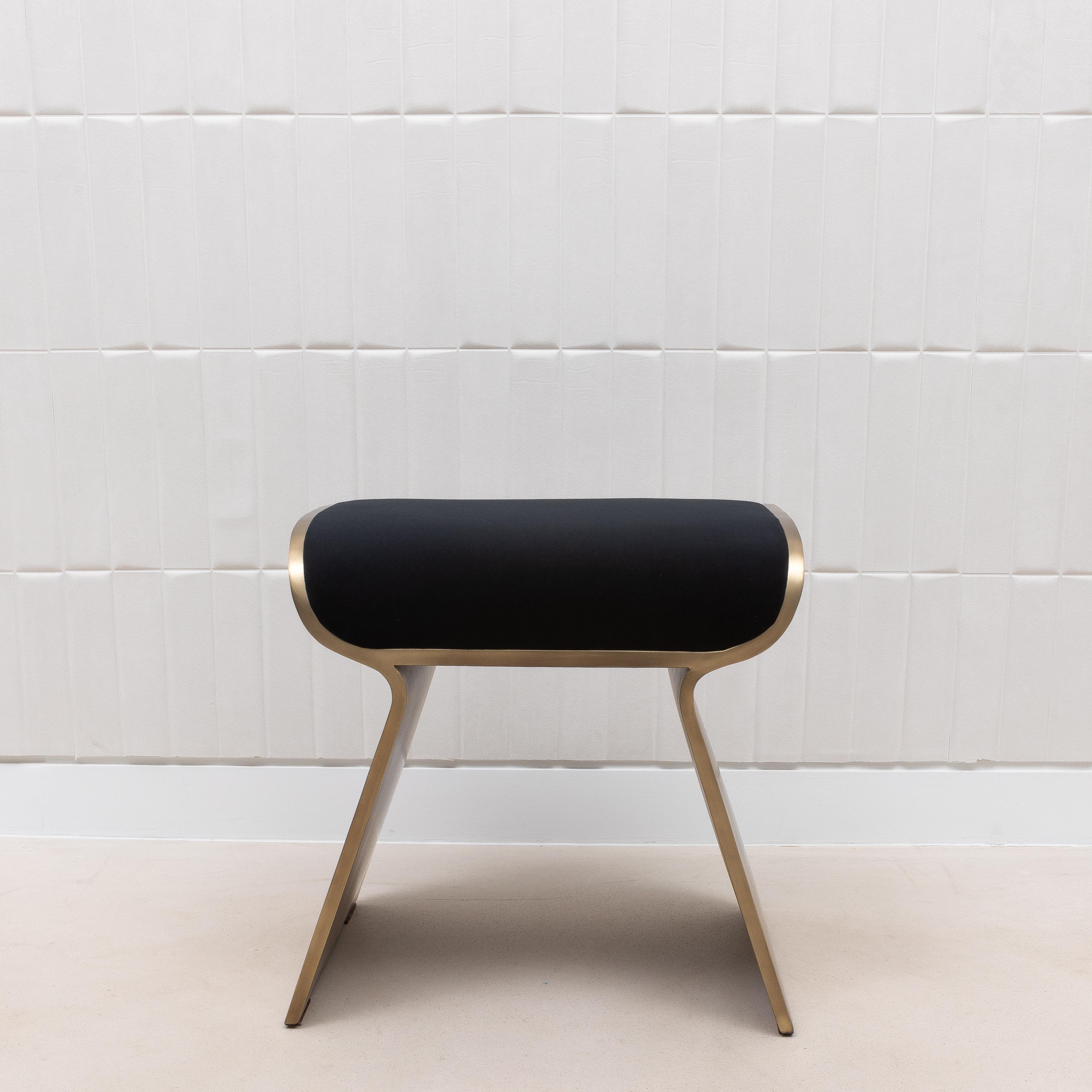 The Dandy Stool by Kifu Paris is a masterful blend of luxury and craftsmanship. This particular stool is upholstered in rich black velvet, providing a sumptuous contrast to the sleek bronze patina brass legs that curve elegantly to create a