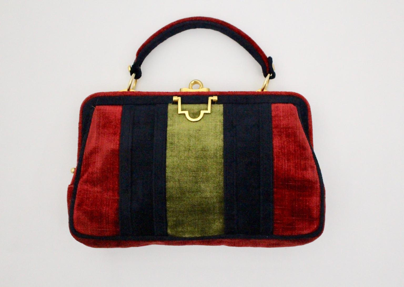 This mid century modern velvet vintage handle bag in the style of Roberta di Camerino is a gorgeous piece from the 1960s, Italy. The surface of the handle bag contrasts the colors red, blue and green and shows also brass details. One pull down snap