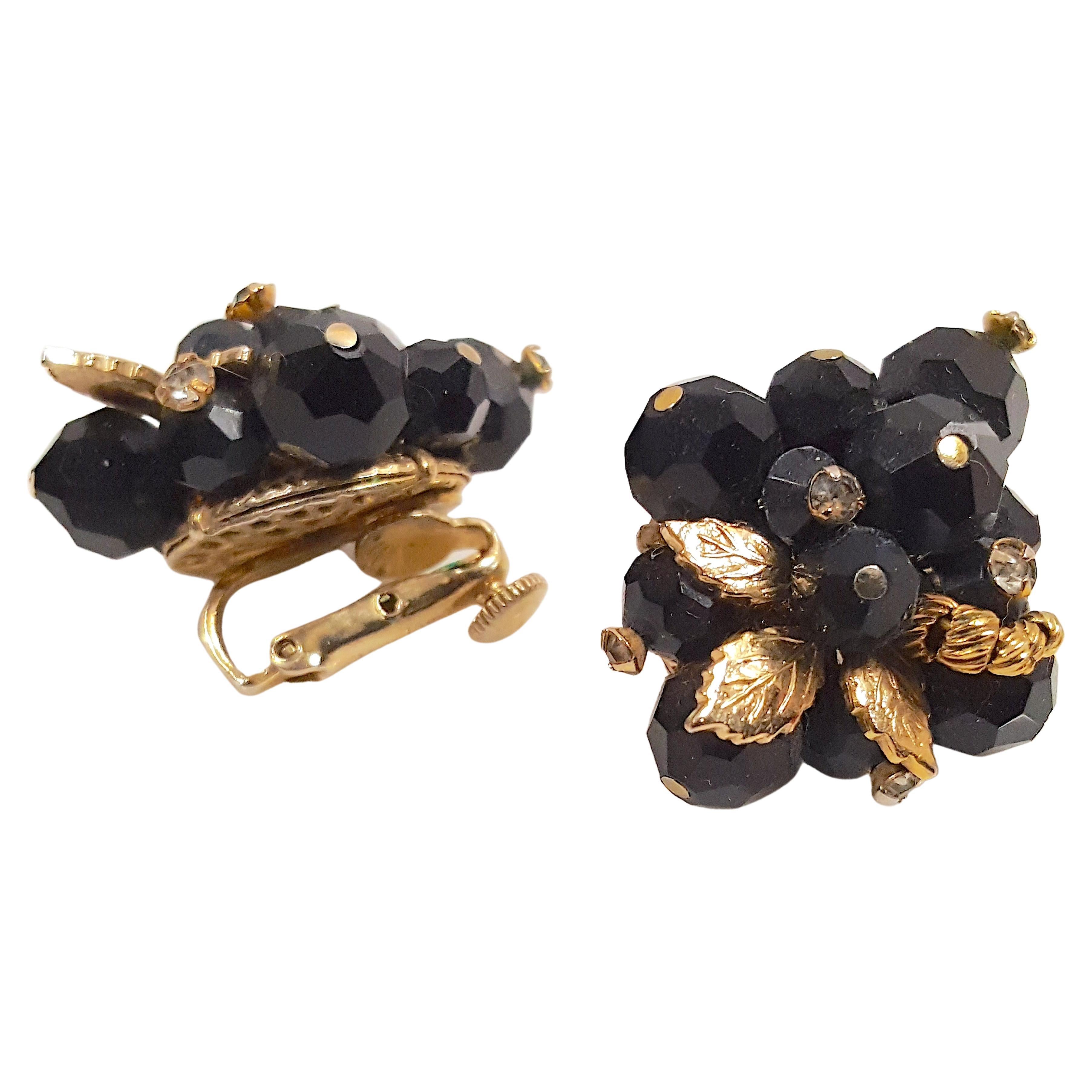 These post-WWII high-end Vendome hand-wired clip earrings each feature a spray of yellow-gold gilt-metal leaves with a stylized branch and five prong-set clear crystals among a cluster of faceted black glass beads. When worn on the ear, they are