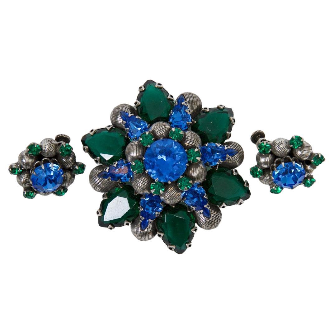 Vendome brooch and earrings set, the brooch of star shape consisting of large pear-shaped green crystals interspersed with sapphire blue round crystals and striated silver beads, all centering a large blue crystal. The coordinating clip-on/screwback