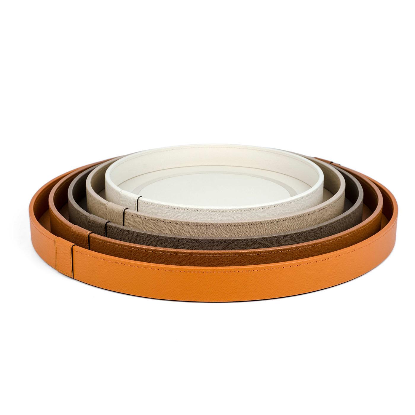 This luxe tray is an exclusive accessory upholstered with orange-dyed calfskin, its solid, opaque shade is only interrupted by a thin, chromed circle accenting the bottom surface. The round shape, the vivid hue, and the soft grain leather all give