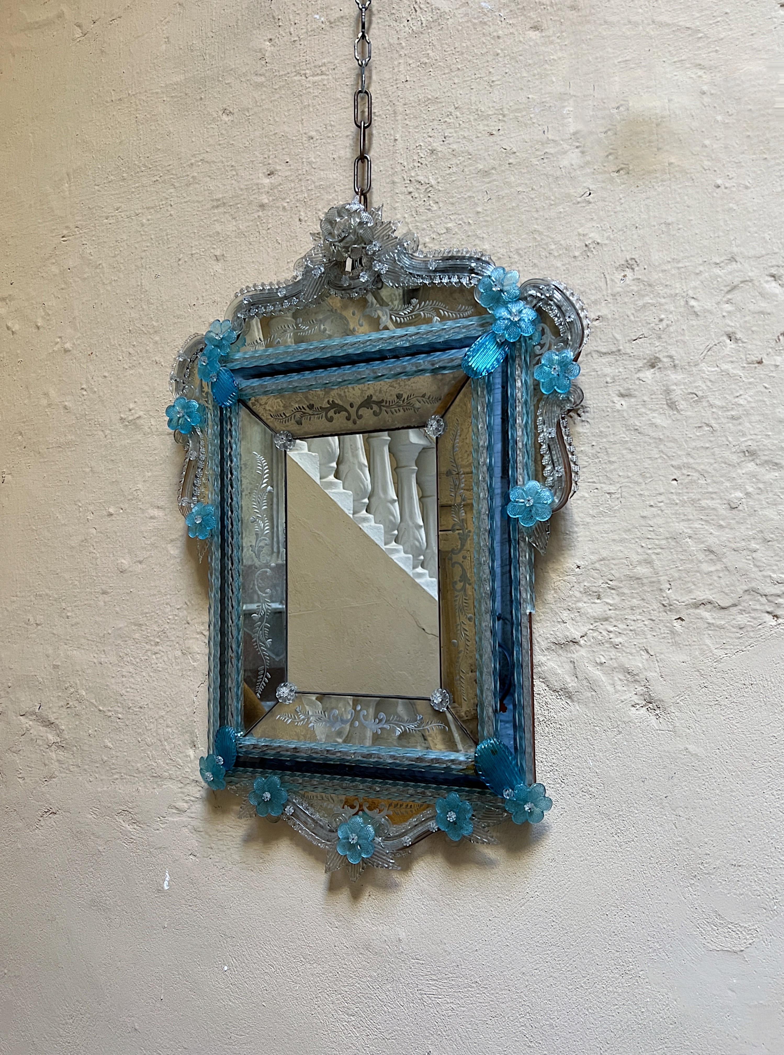 Introducing this Stunning 1920s Blue and Clear Murano Glass Mirror with Florals. 

True vintage elegance with this exquisite 1920s Murano Glass Mirror. Crafted in the famed Murano region of Italy, this mirror showcases a mesmerizing blend of blue