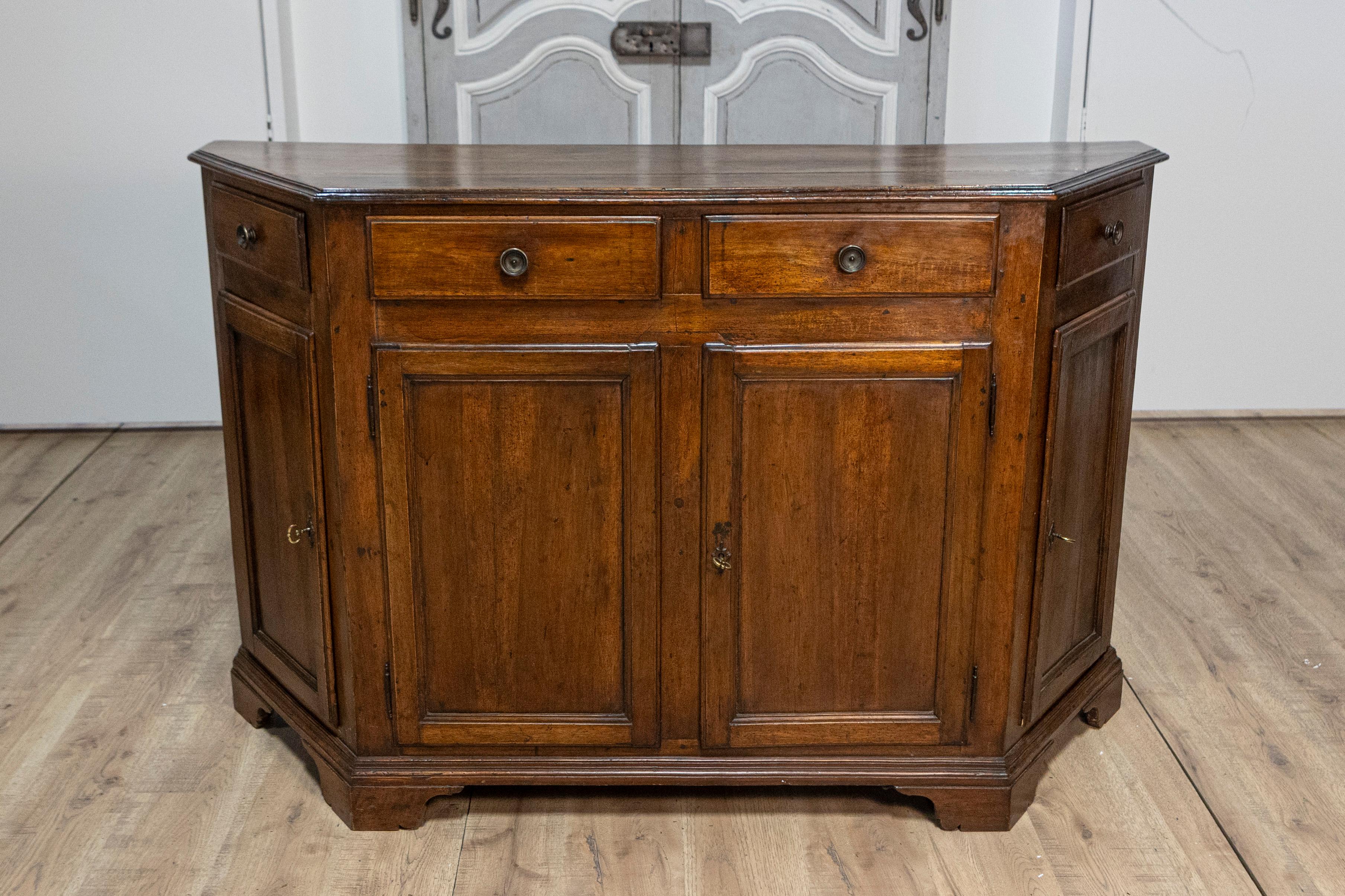 An Italian 19th century walnut credenza from Venice, with canted sides and four drawers over four doors. This exquisite Venetian walnut credenza from the 19th century is a testament to classic craftsmanship and timeless elegance. With its rich