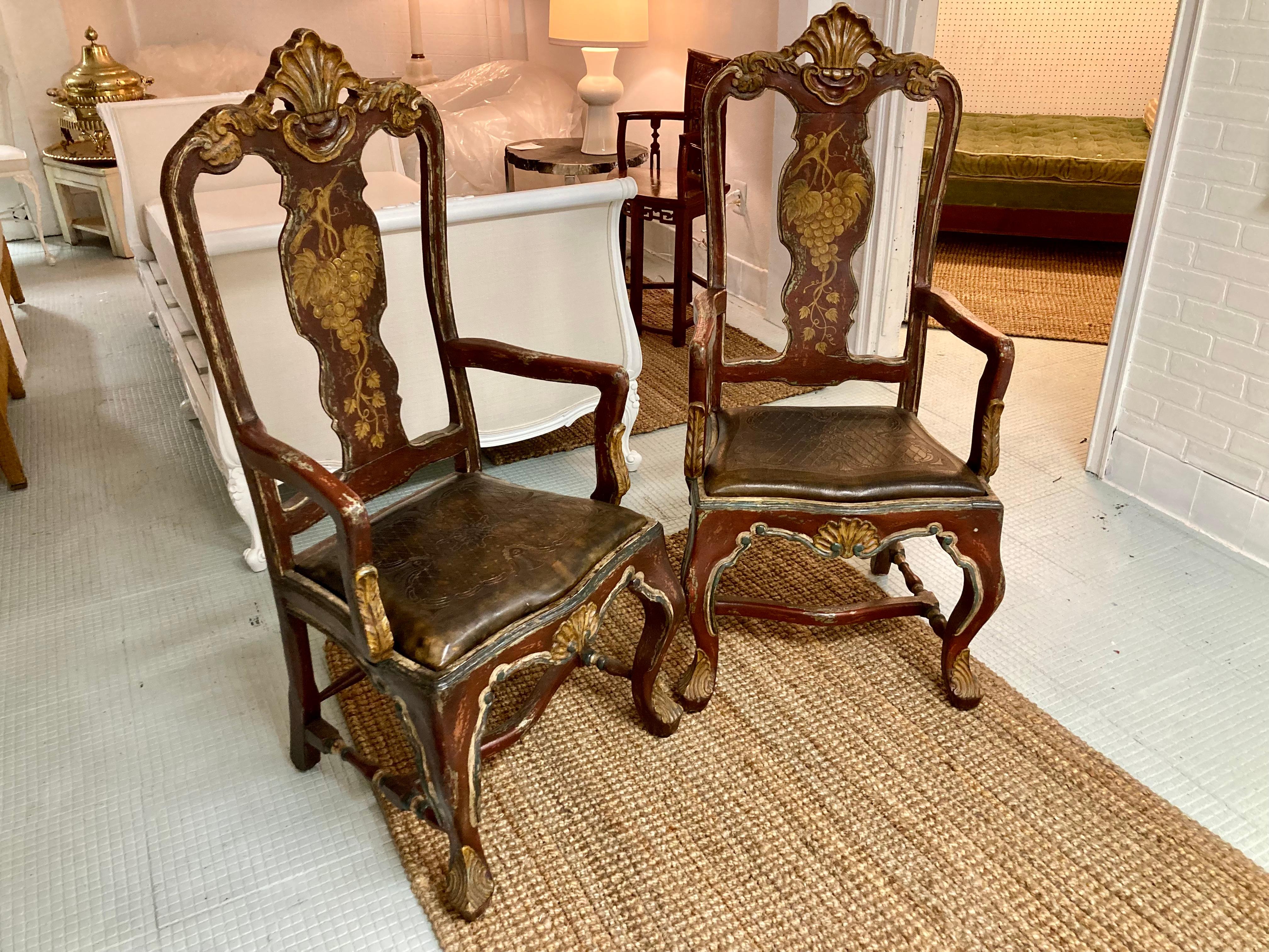 Beautiful pair of Venetian arm chairs with original painted finish and original embossed leather seats. Fabulous detailed carving and original painted finish and decorate gold paintings on the inside and outside backs. Add some Continental style to