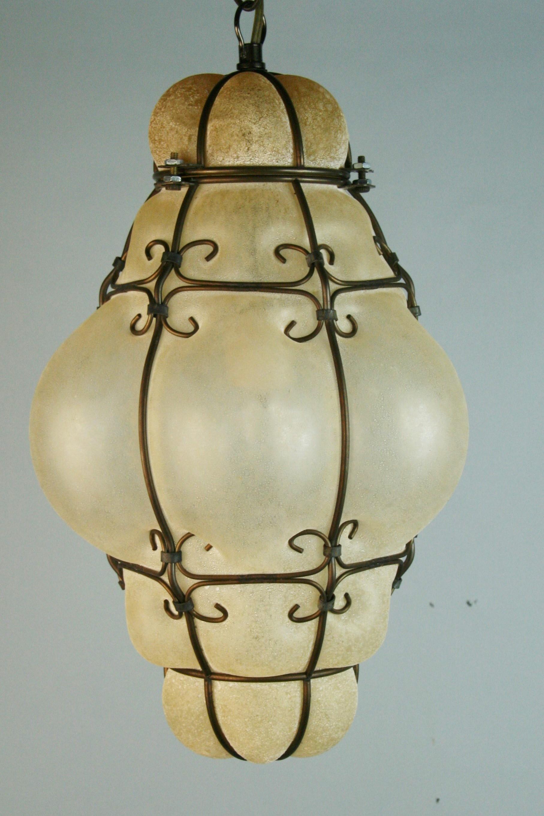 1297 Venetian Clear glass pendant in wire cage with embedded sand finish.